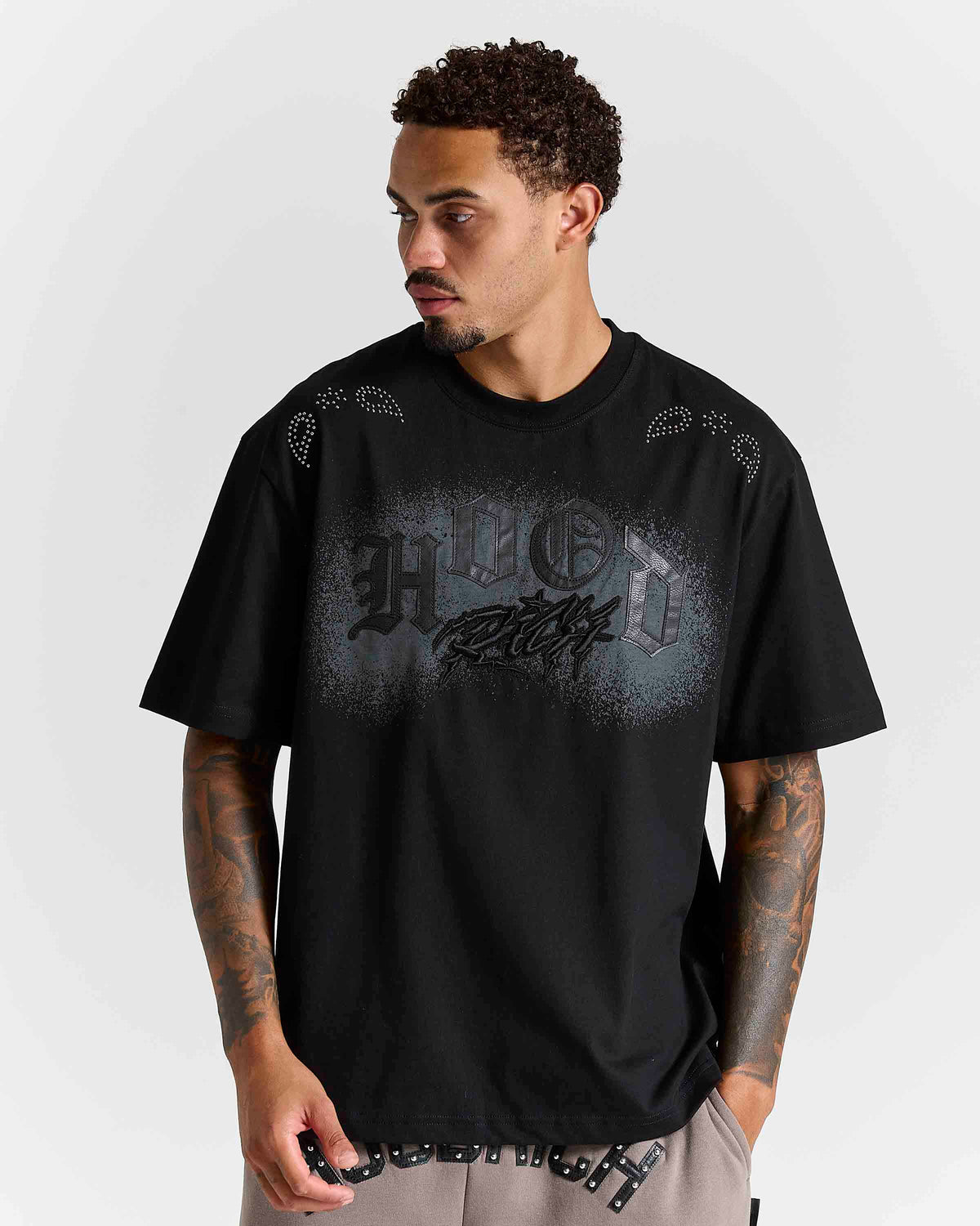 Displays a model wearing the Black 'Hoodrich' branded Inkline V2 Oversized Tshirt