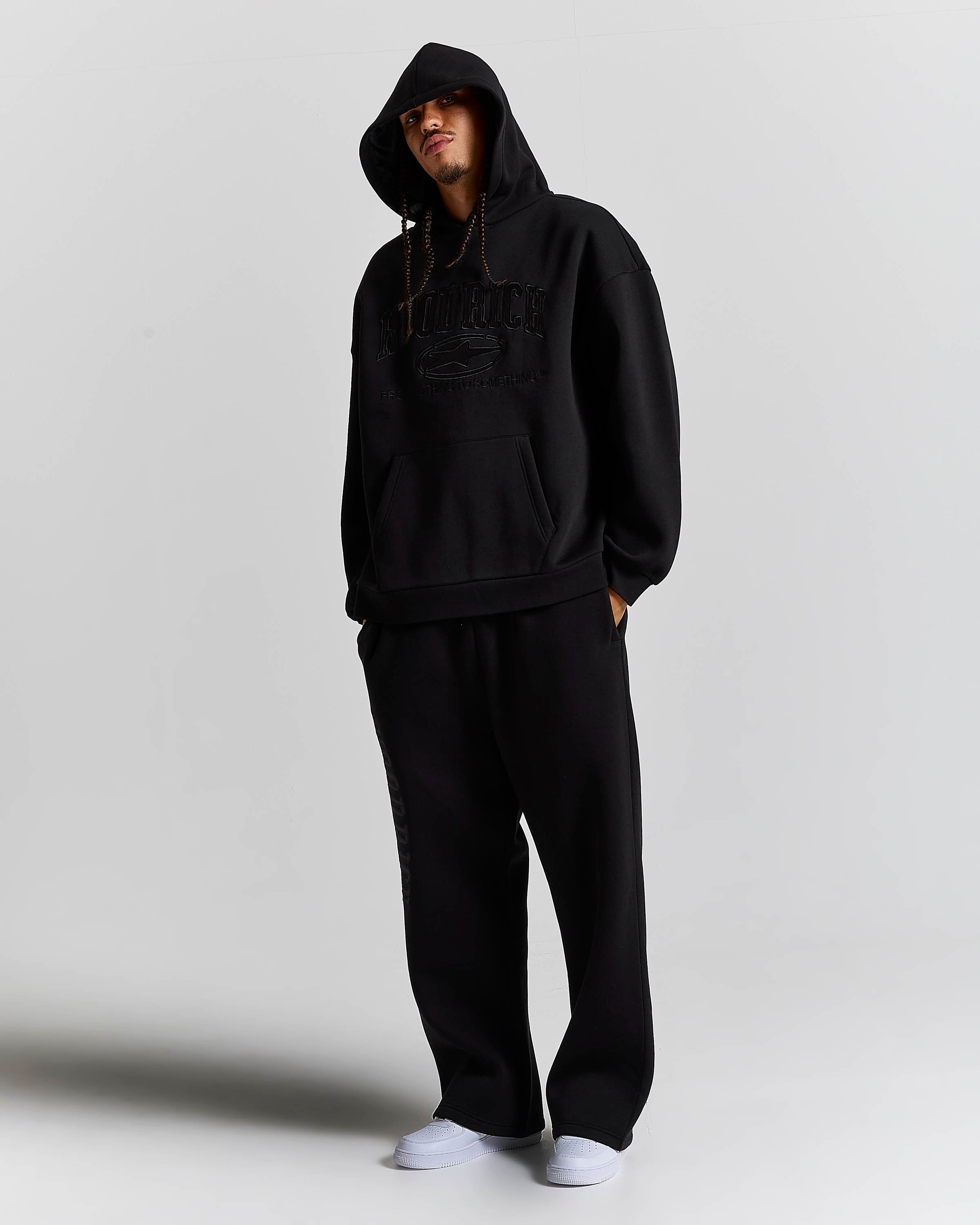 Displays a model wearing the Black 'Hoodrich' branded men's Aegis Full Tracksuit