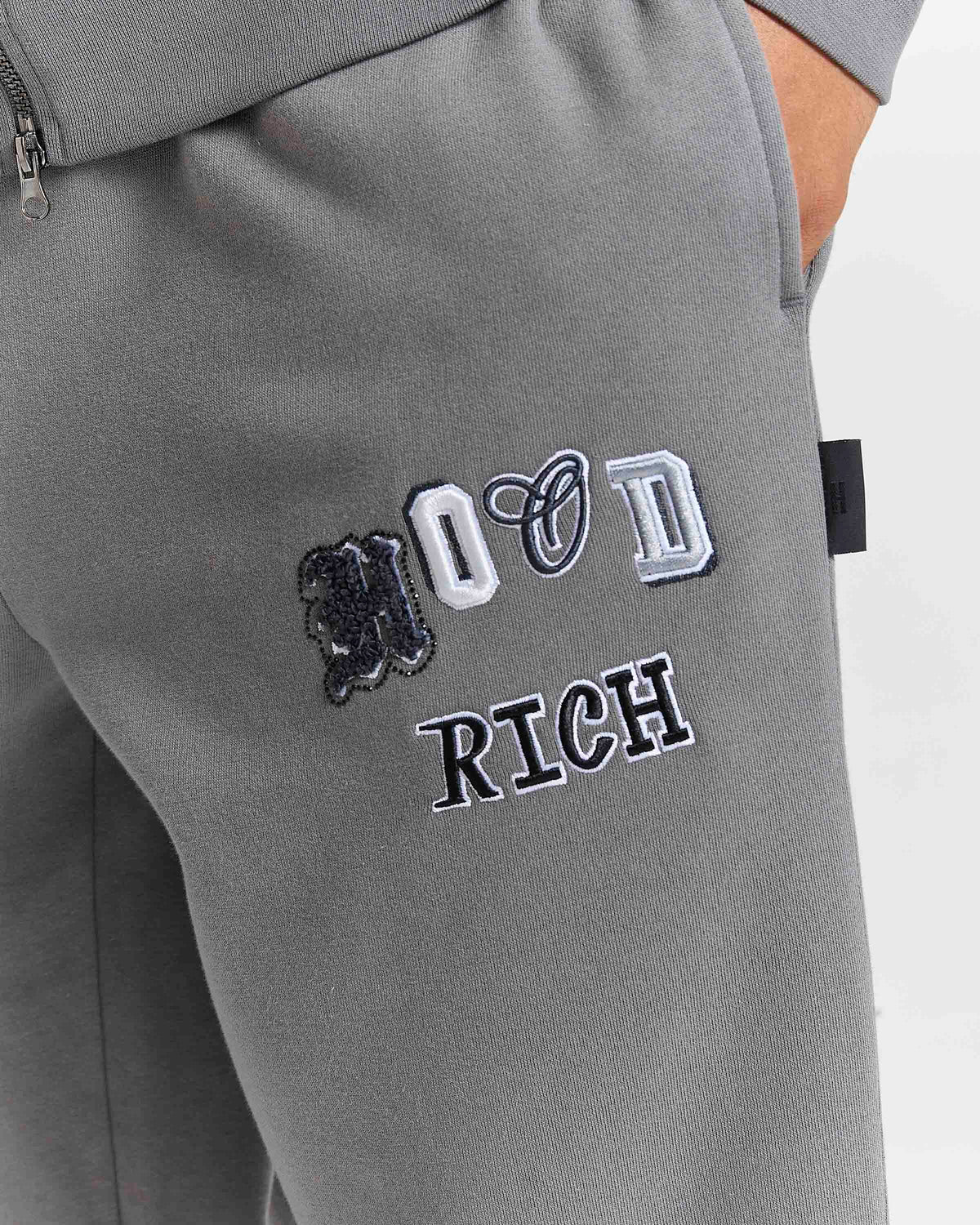 Displays a model wearing the Grey 'Hoodrich' branded men's Forza Full Tracksuit featuring the hoodrich branding