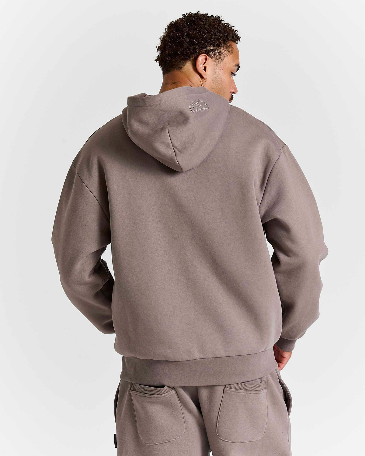 Displays a model wearing the Falcon Black 'hoodrich' branded Varso Studs Oversized Zip Through Hoodie