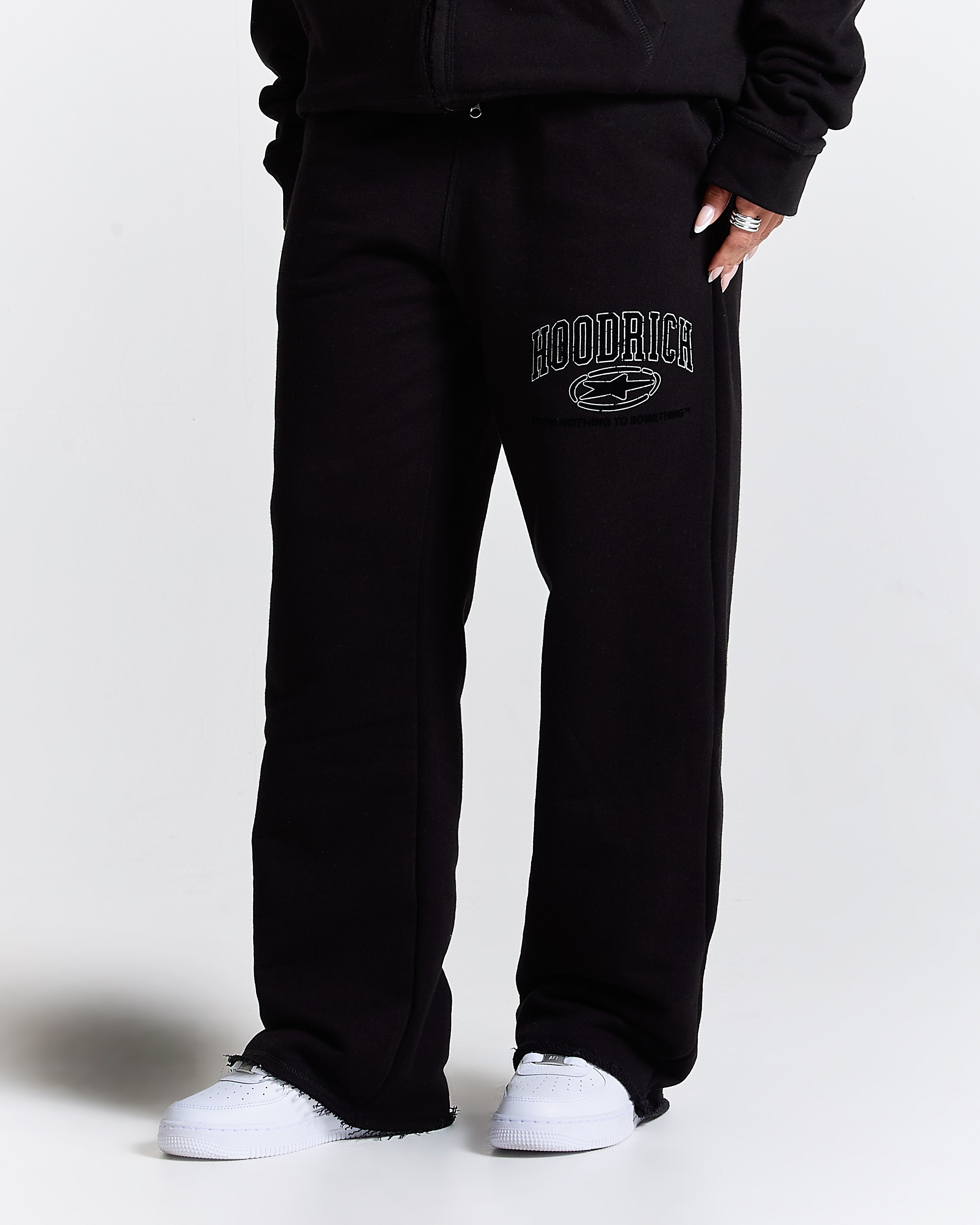 Person wearing black sweatpants with 'Hoodrich' logo on a white background