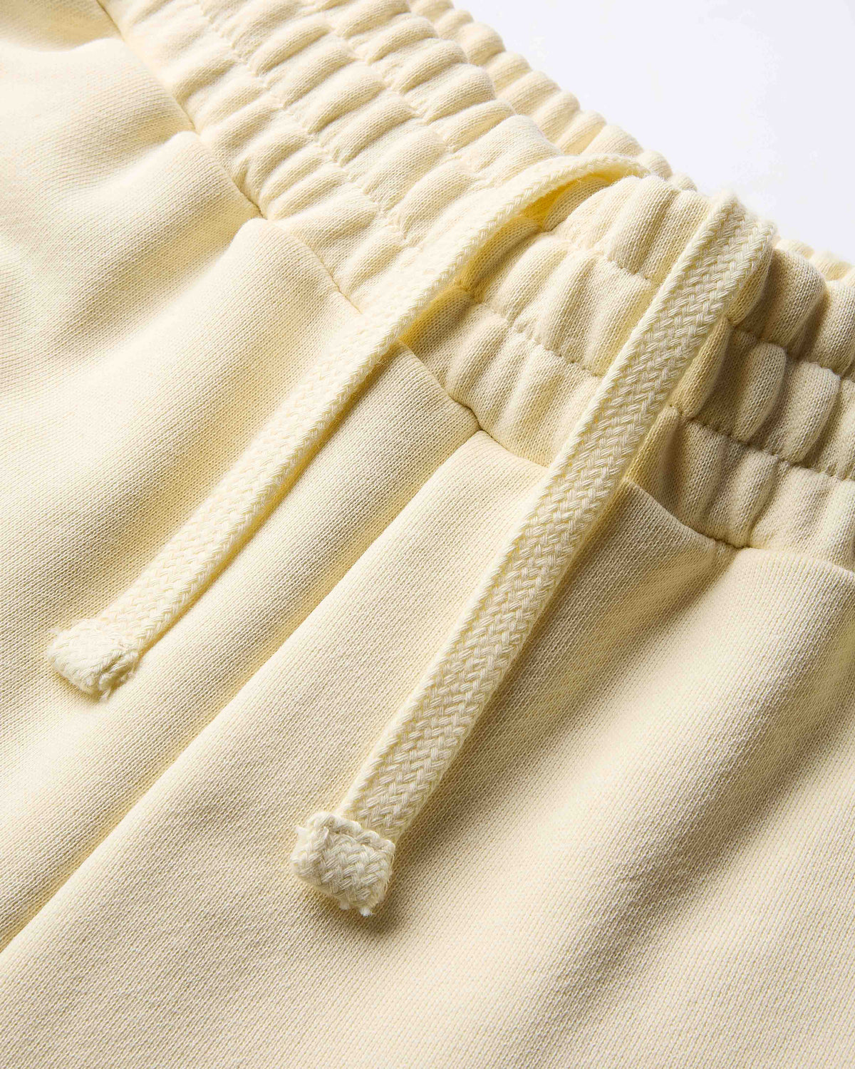 Close-up of cream-colored pants with textured drawstring waistband on a light background