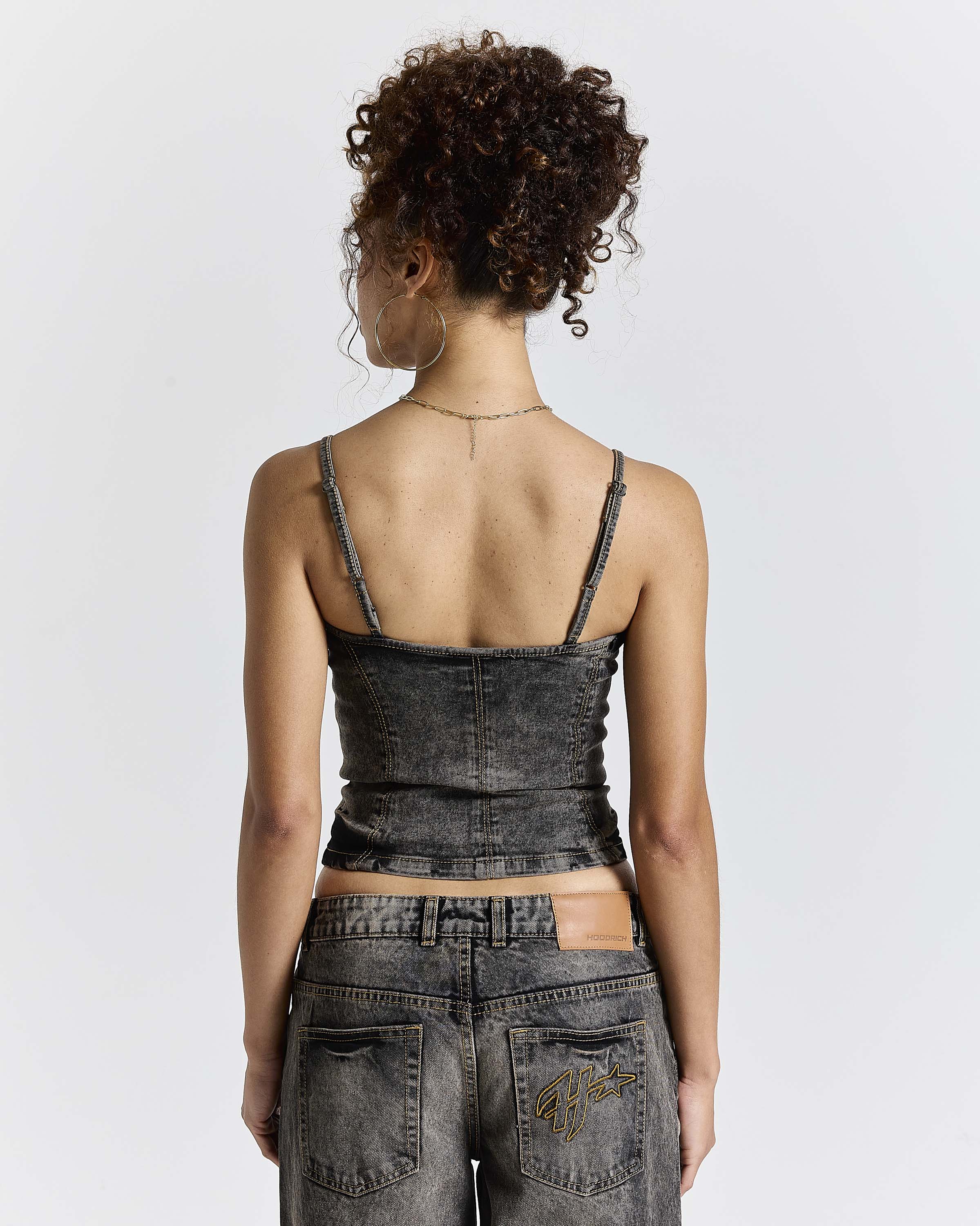 Model seen from behind wearing a fitted black denim corset top and matching jeans.