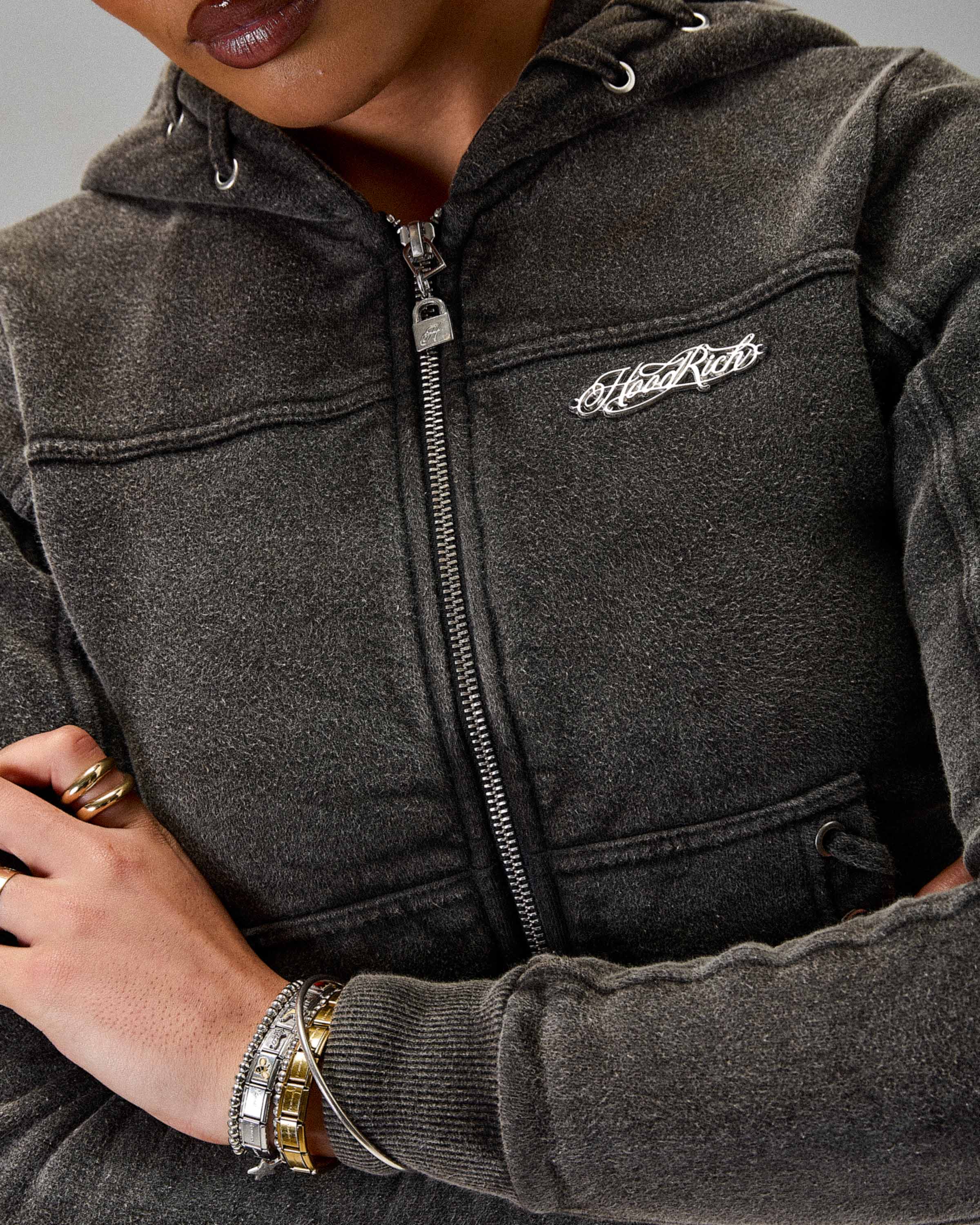 Person wearing a dark gray hoodie with a brand logo on a neutral background