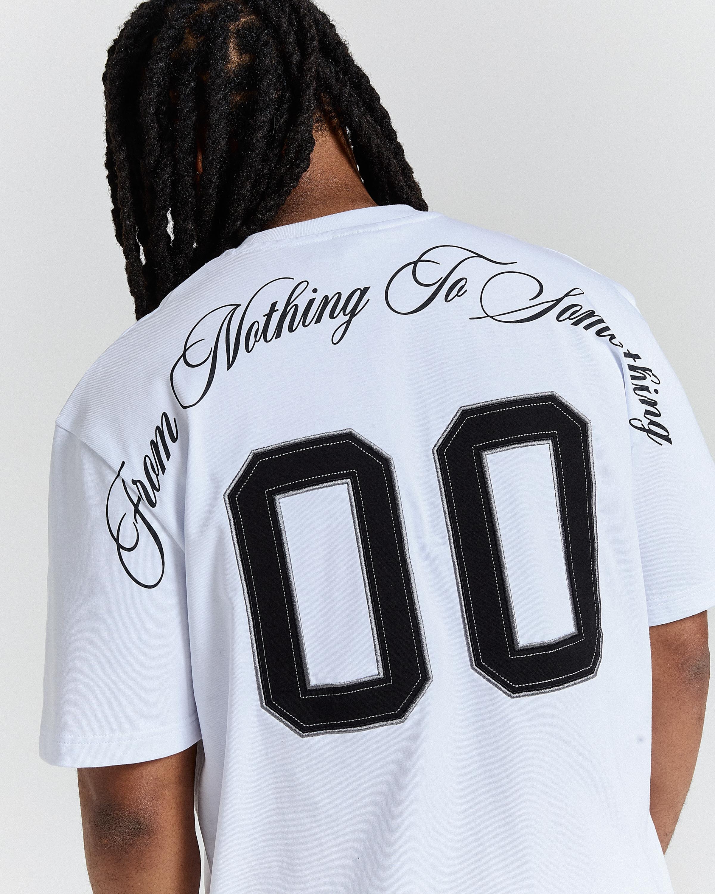 Person wearing a white t-shirt with black text and numbers on the back against a plain background