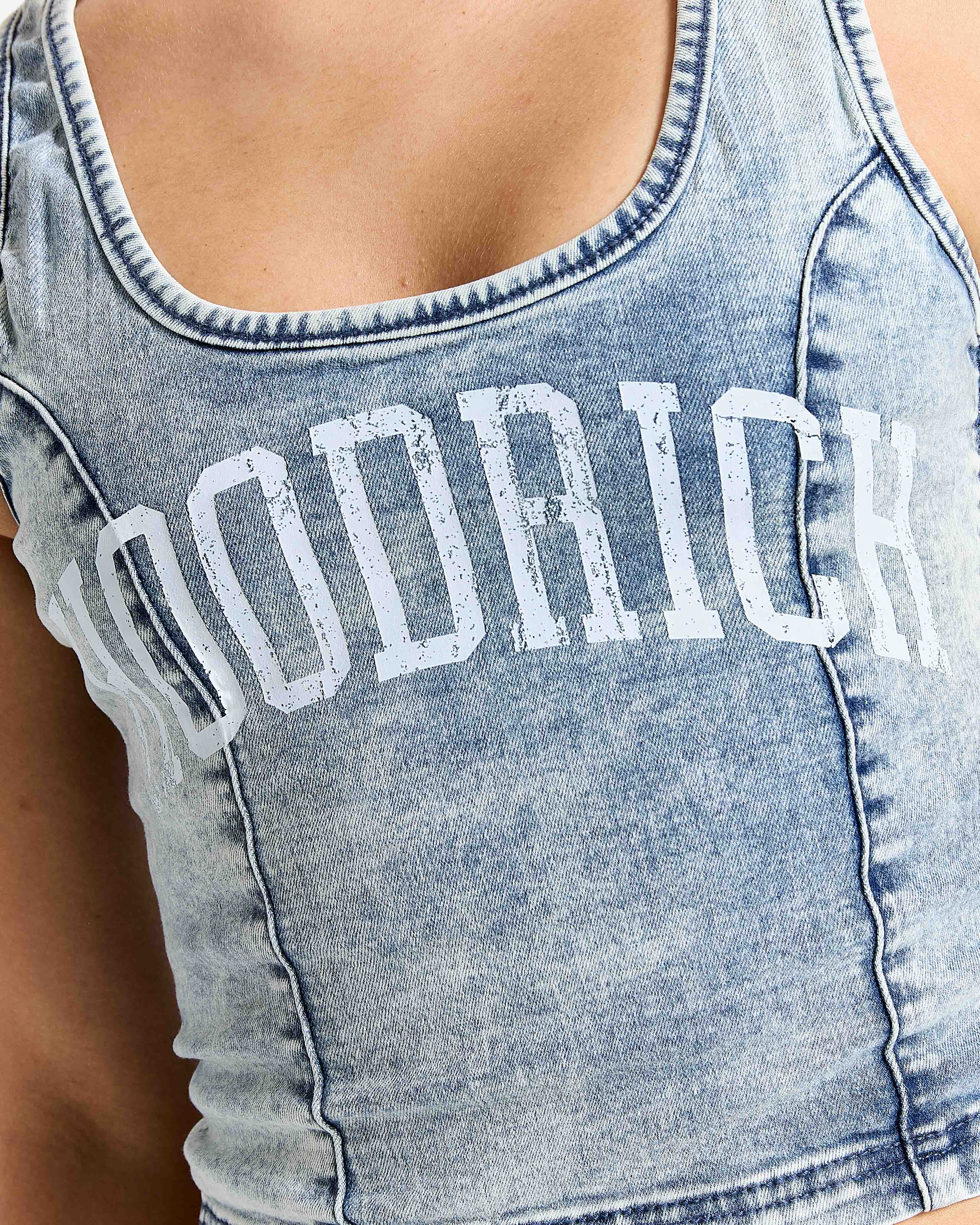 Denim tank top with 'HOODRICH' branding on a blurred background