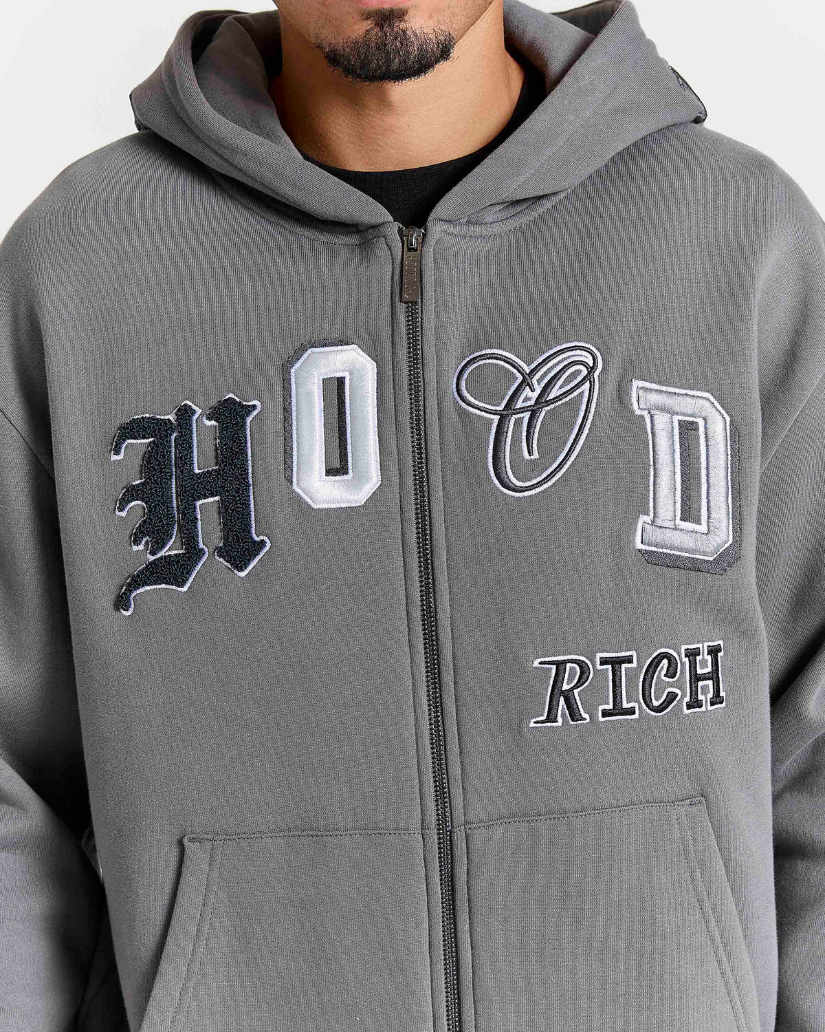Displays a model wearing the Grey 'Hoodrich' branded men's Forza Full Tracksuit featuring the details on the hoodrich branding 