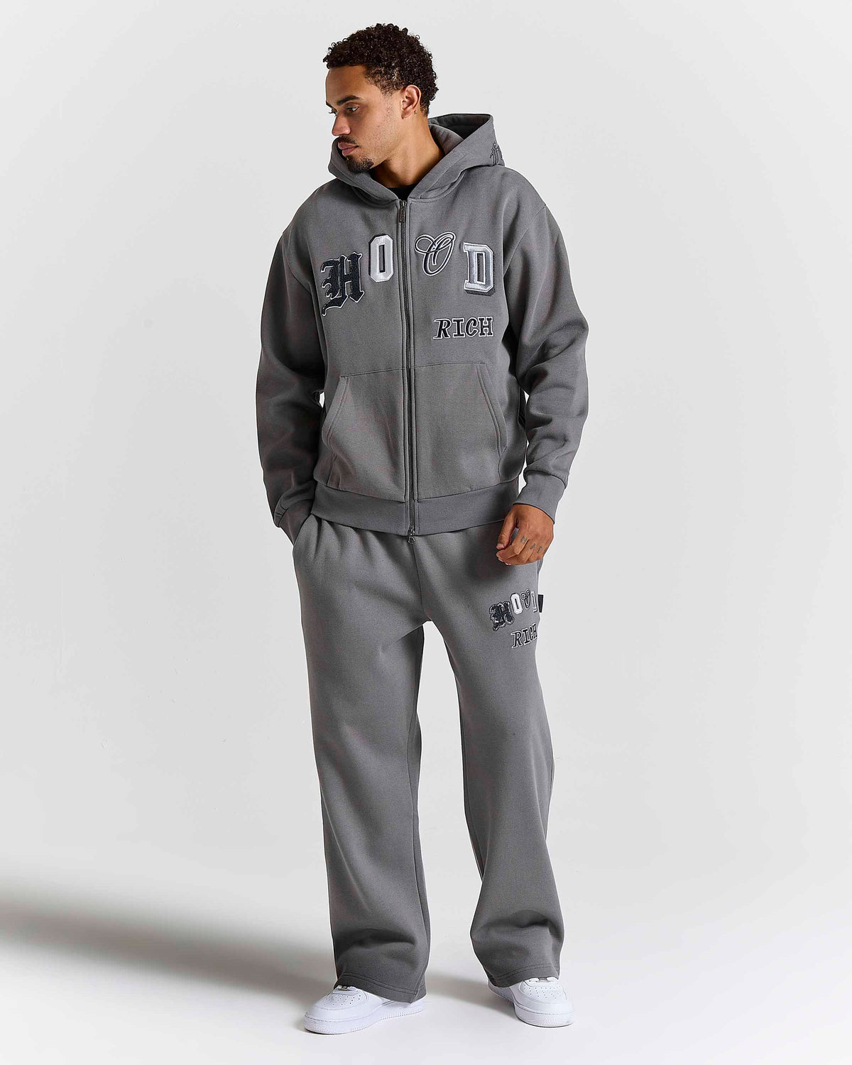 Displays a model wearing the grey lava smoke 'Hoodrich' branded Forza Oversized Zip Through Hoodie 