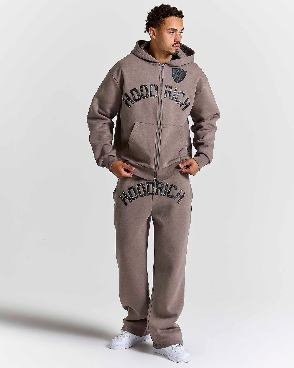 Displays a model wearing the Falcon Black 'Hoodrich' branded Varso Studs Oversized Wide Leg Jogger