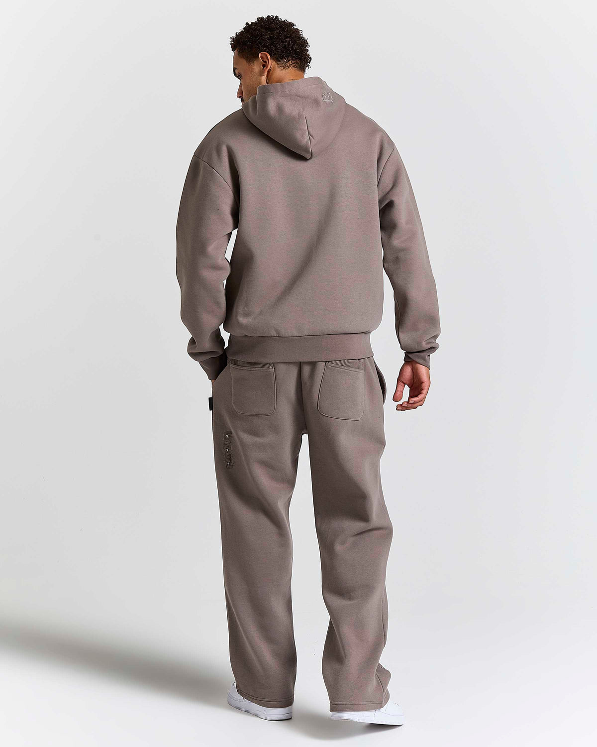 Displays a model wearing the Brown 'Hoodrich' branded men's Varso Studs Full Tracksuit 