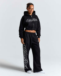 Displays a model wearing the Black 'Hoodrich' branded women's Solace Full Tracksuit 