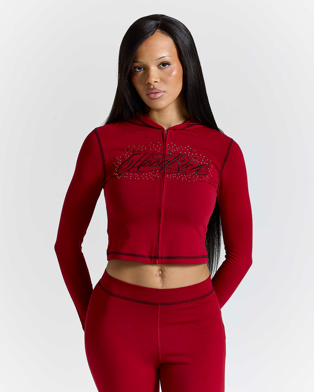 Displays a model wearing the red 'hoodrich' branded Gleam V2 Fitted Z/T Hoodie 
