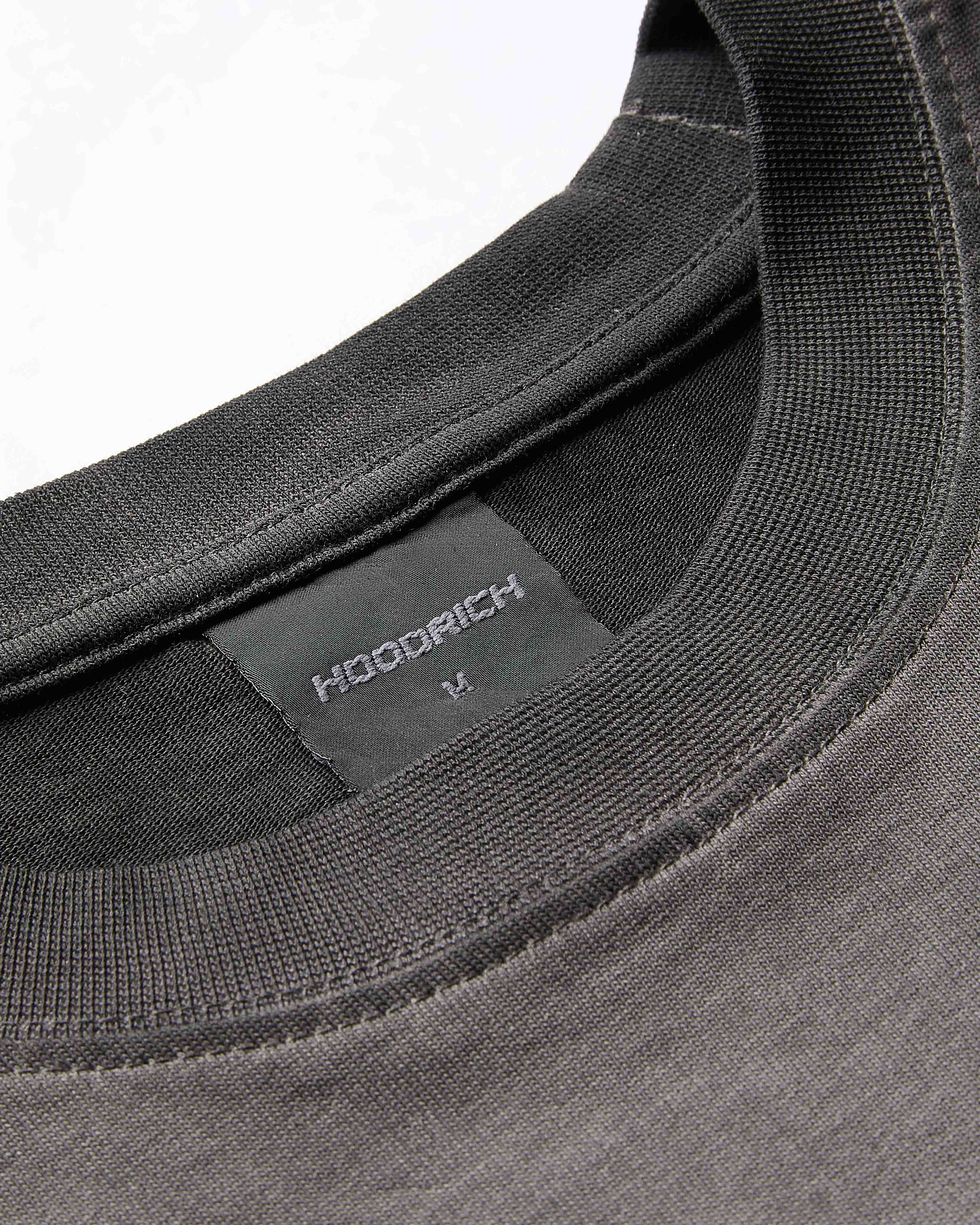 Close-up of the ribbed neckline and branded neck label on an oversized black oil wash t-shirt.