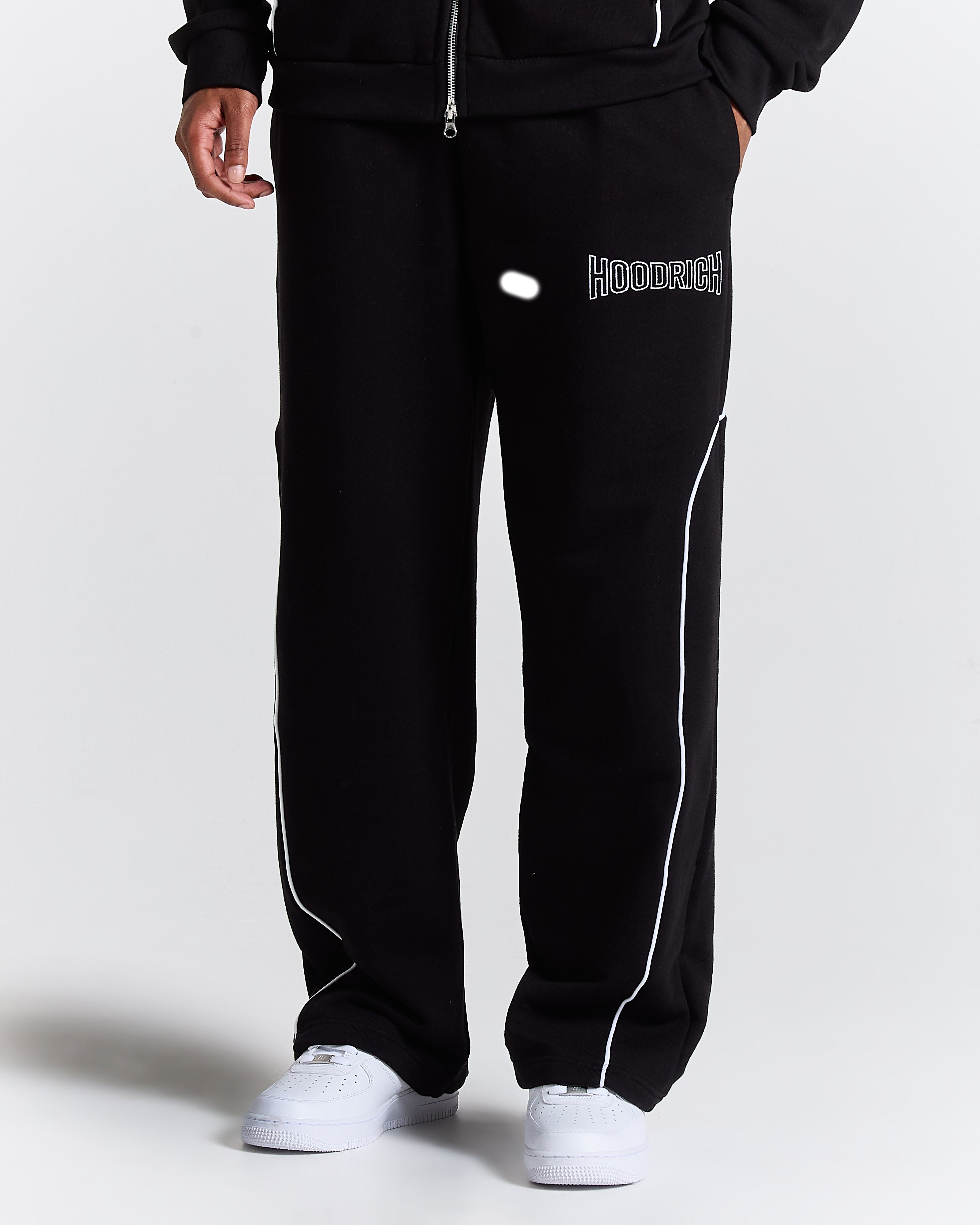 Black tracksuit with white piping on a plain background