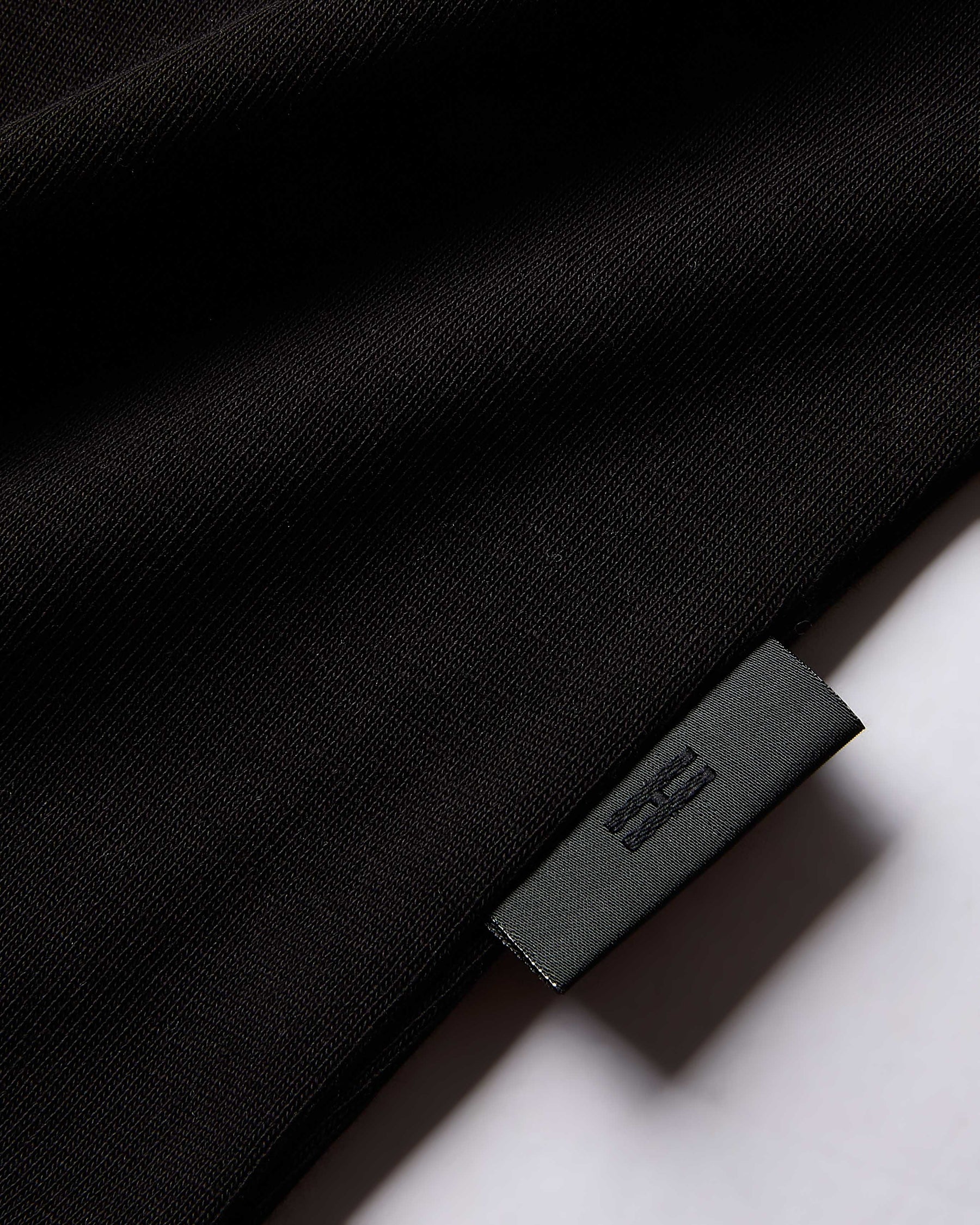 Close-up of a black garment with a brand label on a white background