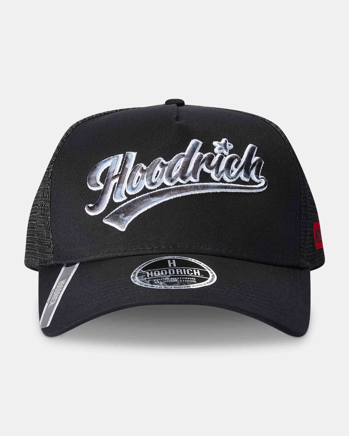 A black trucker-style cap with a curved brim, black mesh back panels, and a large metallic silver 'Hoodrich' logo on the front. A smaller silver reflective accent is visible on the underside of the brim, and a small red tag is on the side.