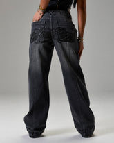 Black jeans with decorative stitching on a gray background