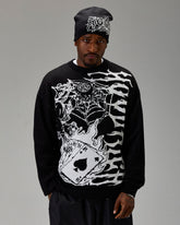 Person wearing a black sweater with white graphic design and a matching beanie on a gray background