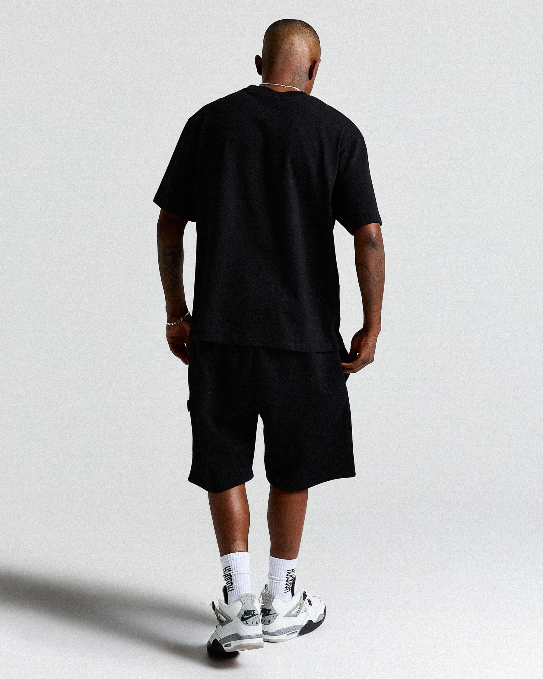 Person wearing a black t-shirt and shorts set on a light gray background