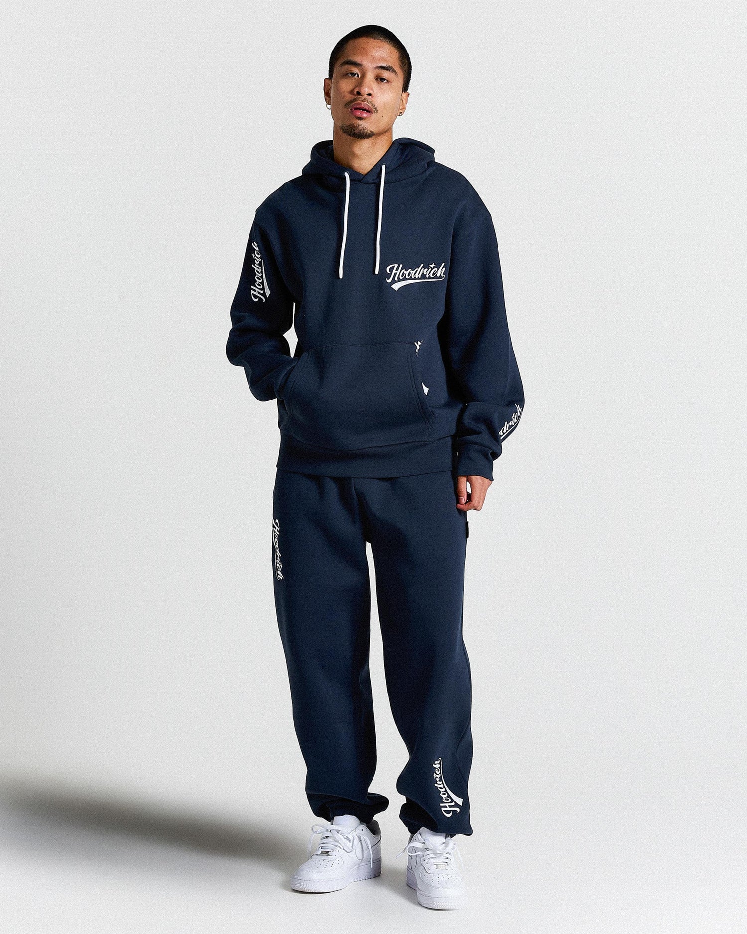 Person wearing a navy tracksuit with brand logo on a white background