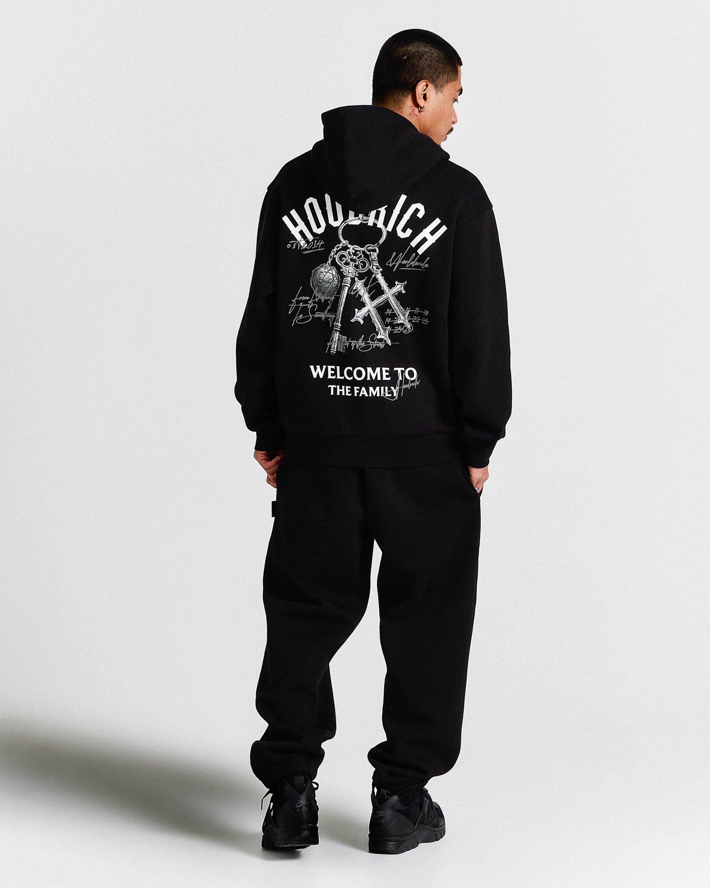 Person wearing a black hoodie with text and graphics on the back against a white background