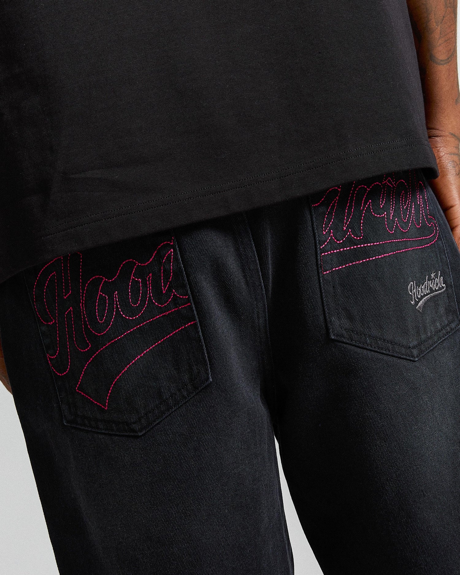 Black pants with red embroidery on a gray background