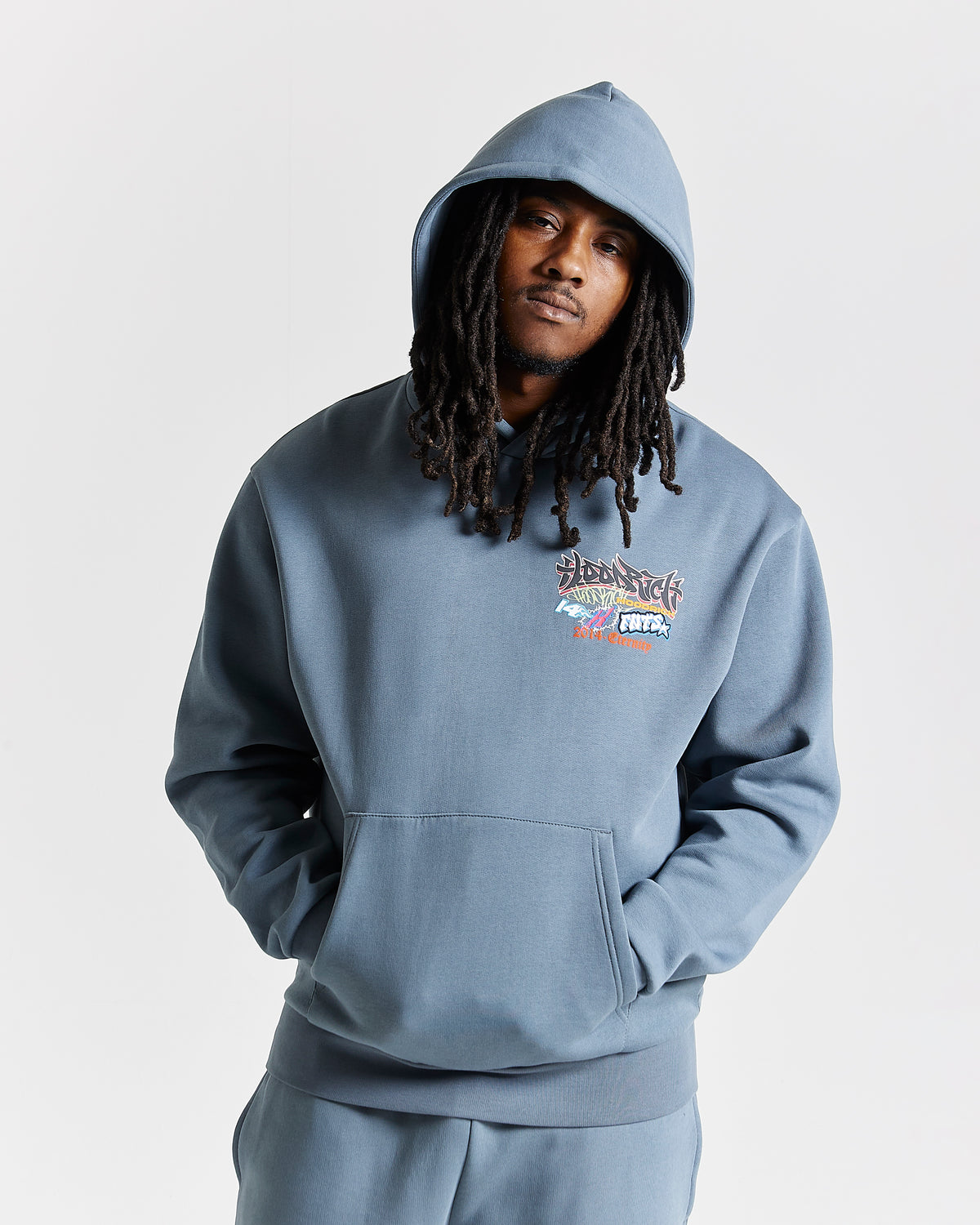 Displays a model wearing the Grey 'Hoodrich' branded men's Graff Rave Full Tracksuit