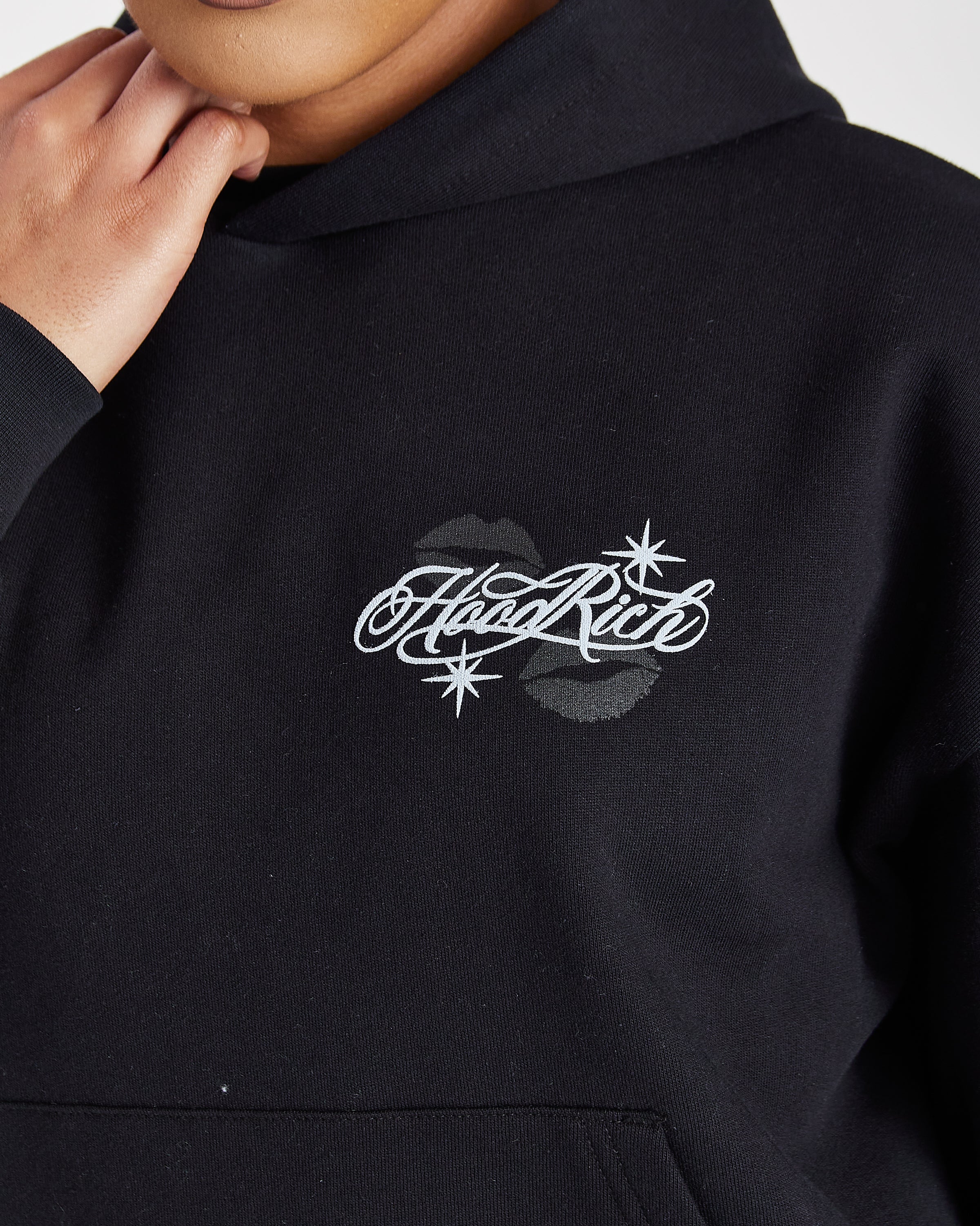 Close-up of a person wearing a black hoodie with a white 'HeadRite' script logo and star graphics on the chest, along with two dark lipstick kiss marks.