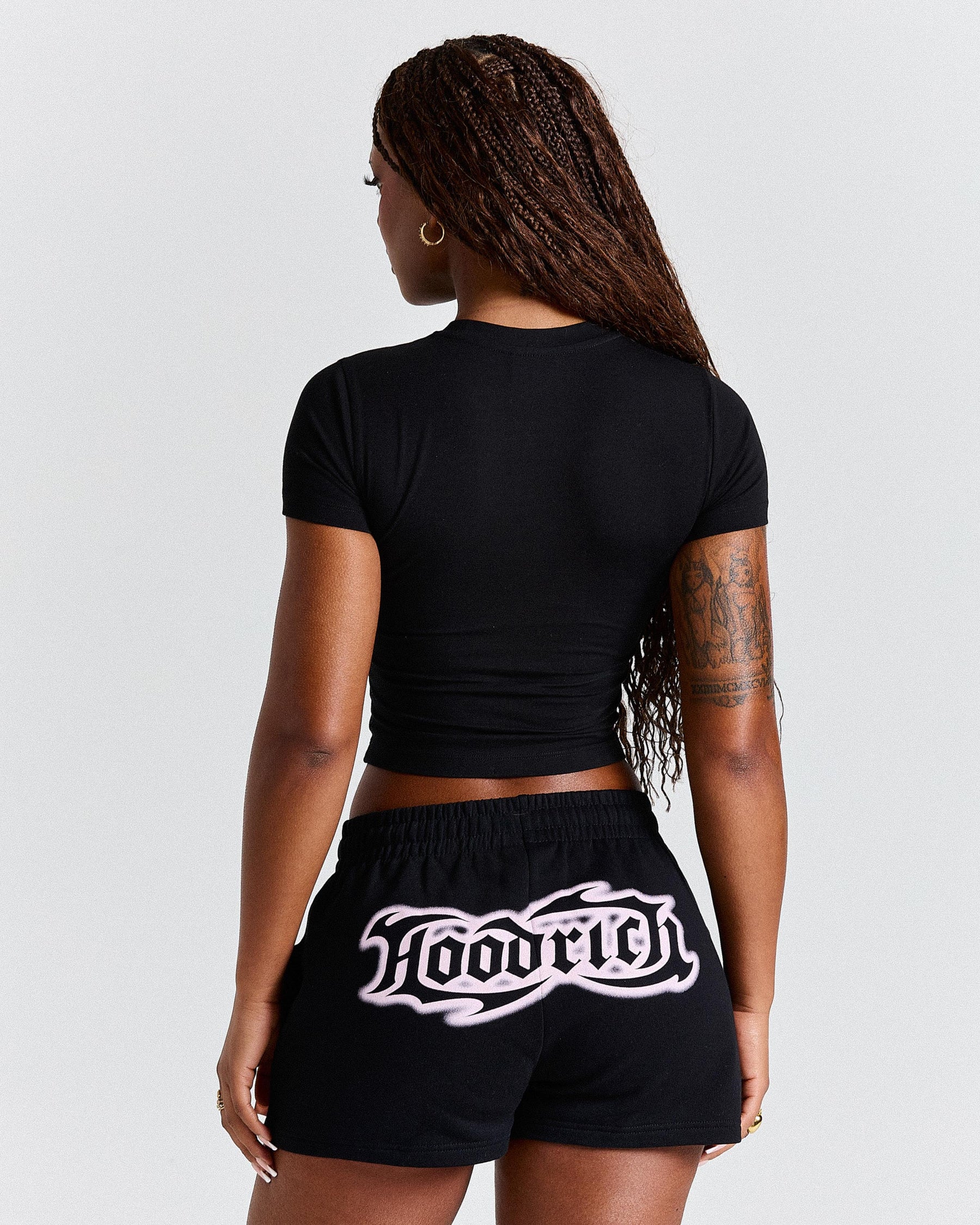 Person wearing a black crop top and black shorts with 'Laoric' branding on a light gray background