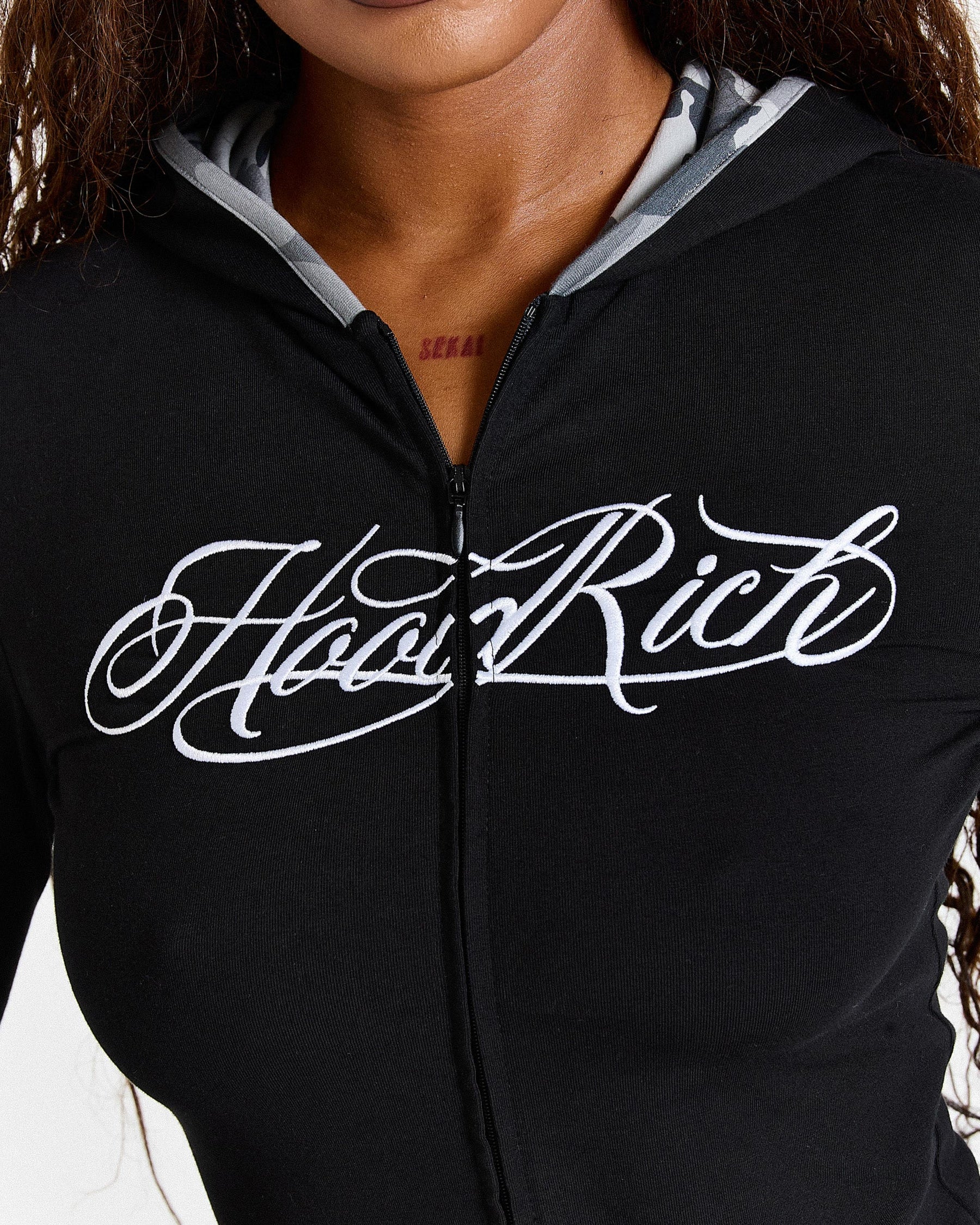 Black hoodie with 'Hoodrich' text on a person wearing it.