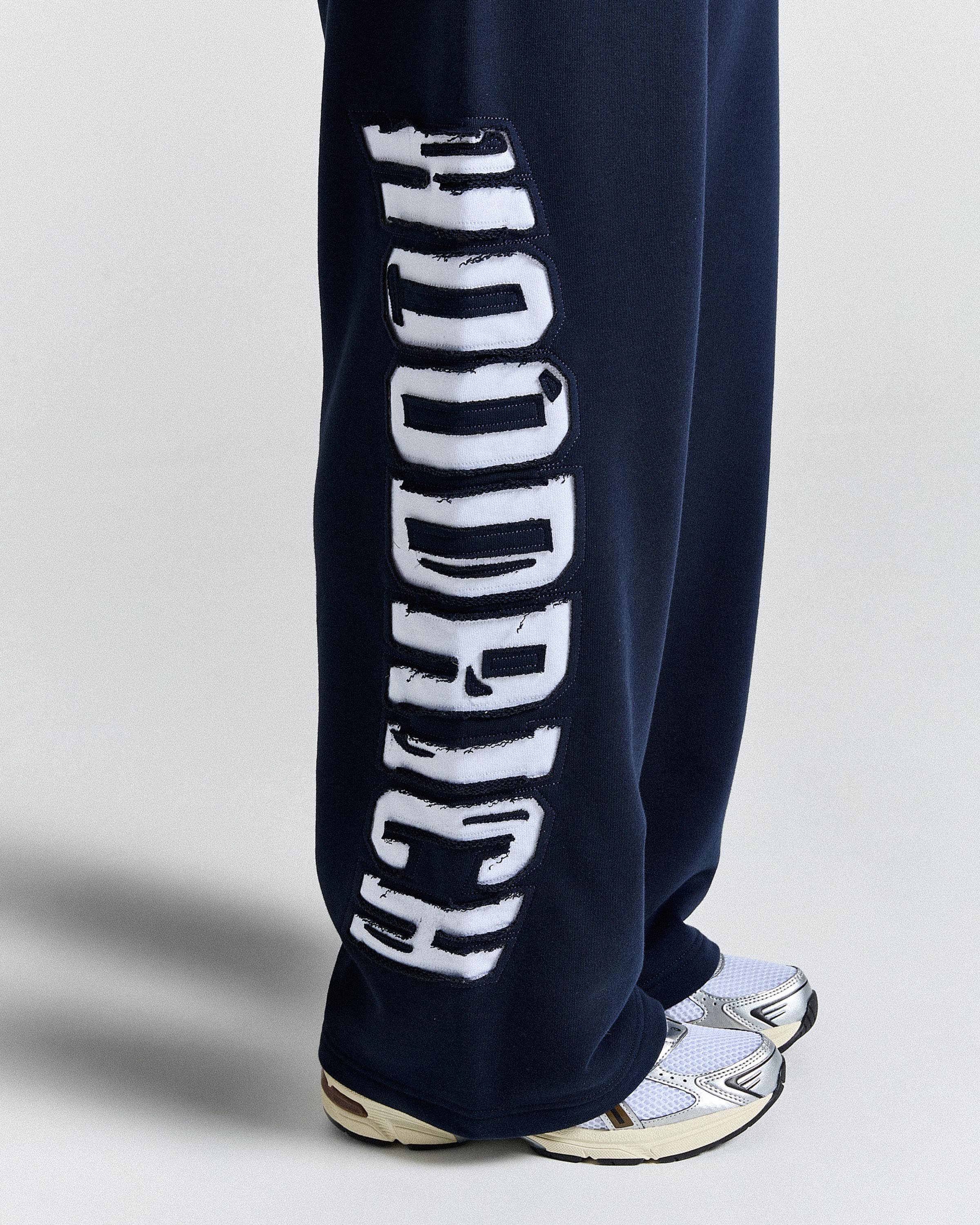 Navy blue sweatpants with white text on a light gray background