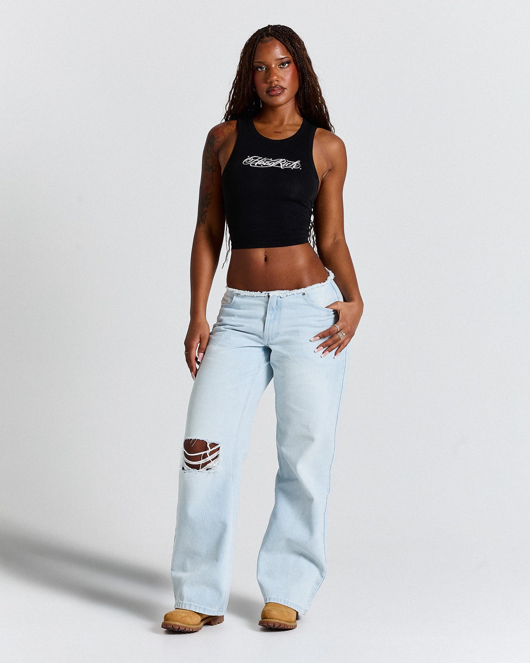 Woman wearing a black crop top and light blue jeans on a white background