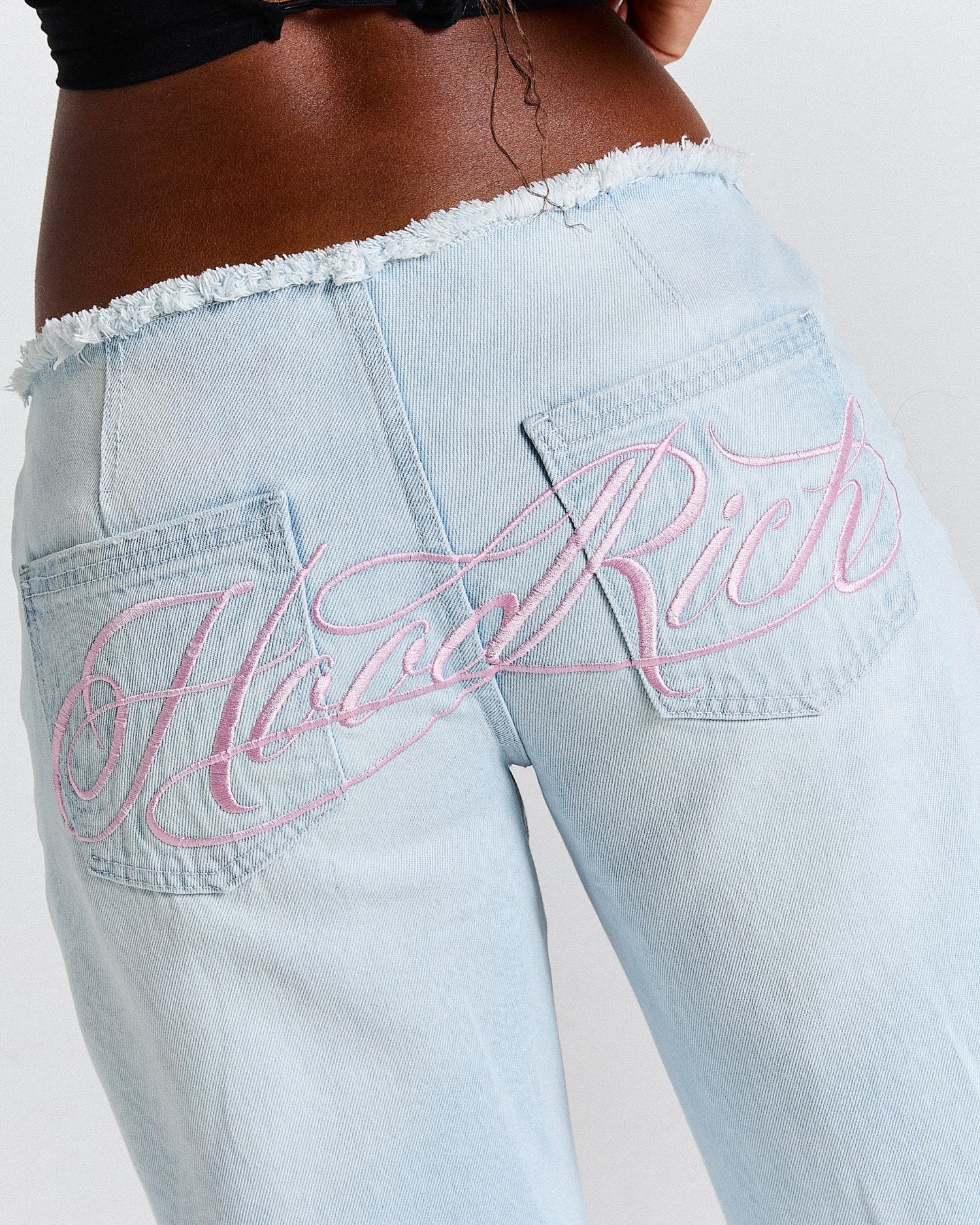 Light blue jeans with pink embroidery on a white background
