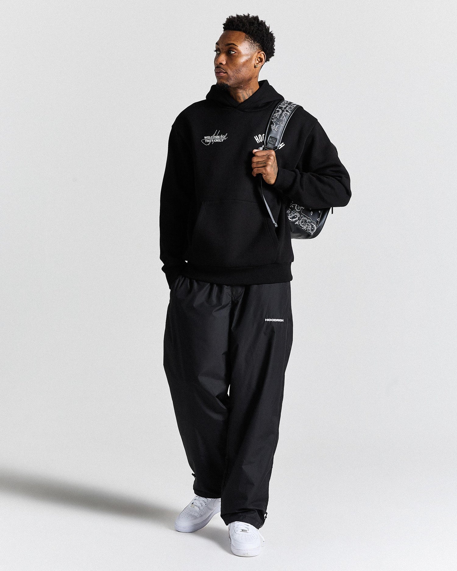 Person wearing a black tracksuit with a brand logo on a white background
