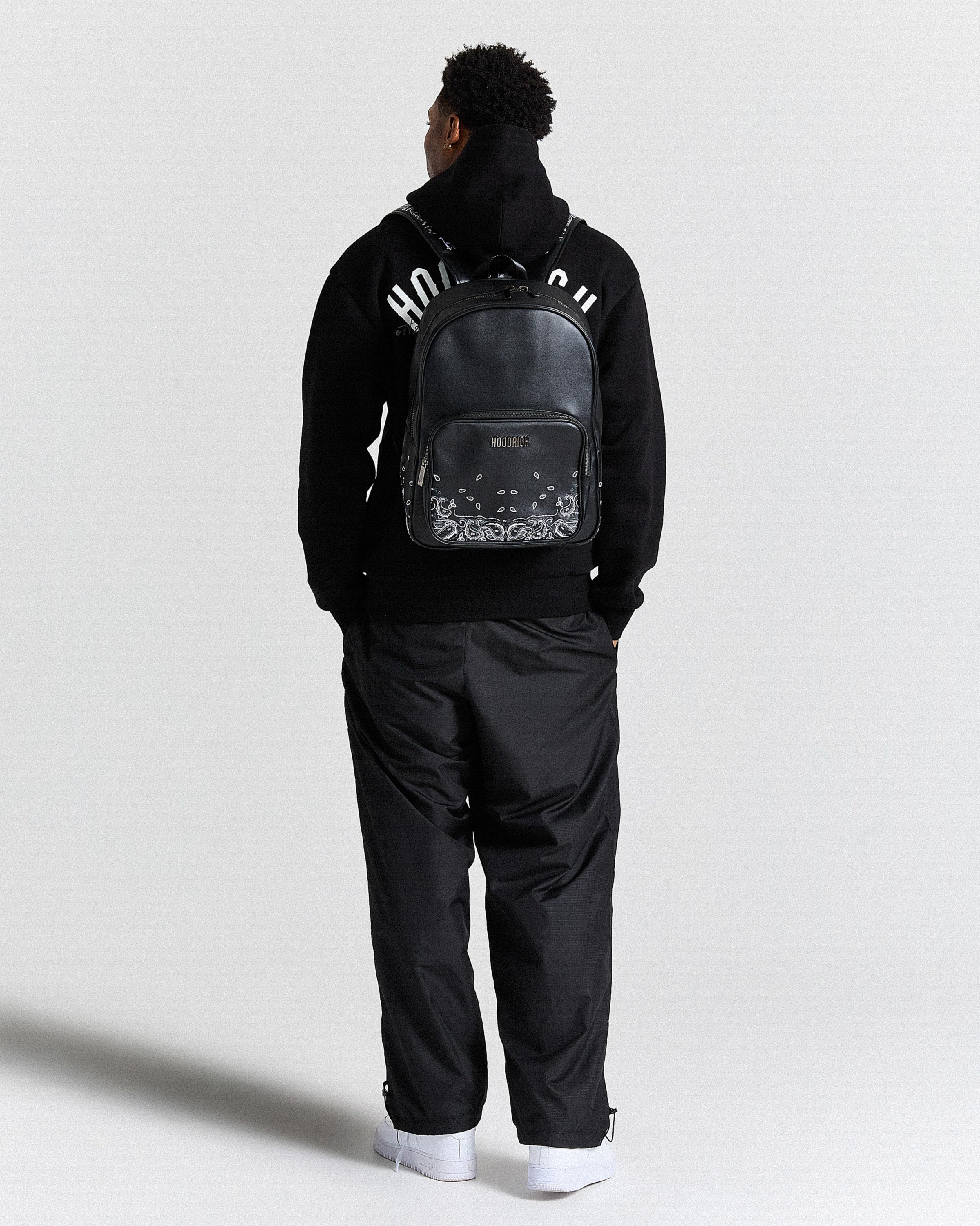 Person wearing a black tracksuit with a backpack on a white background