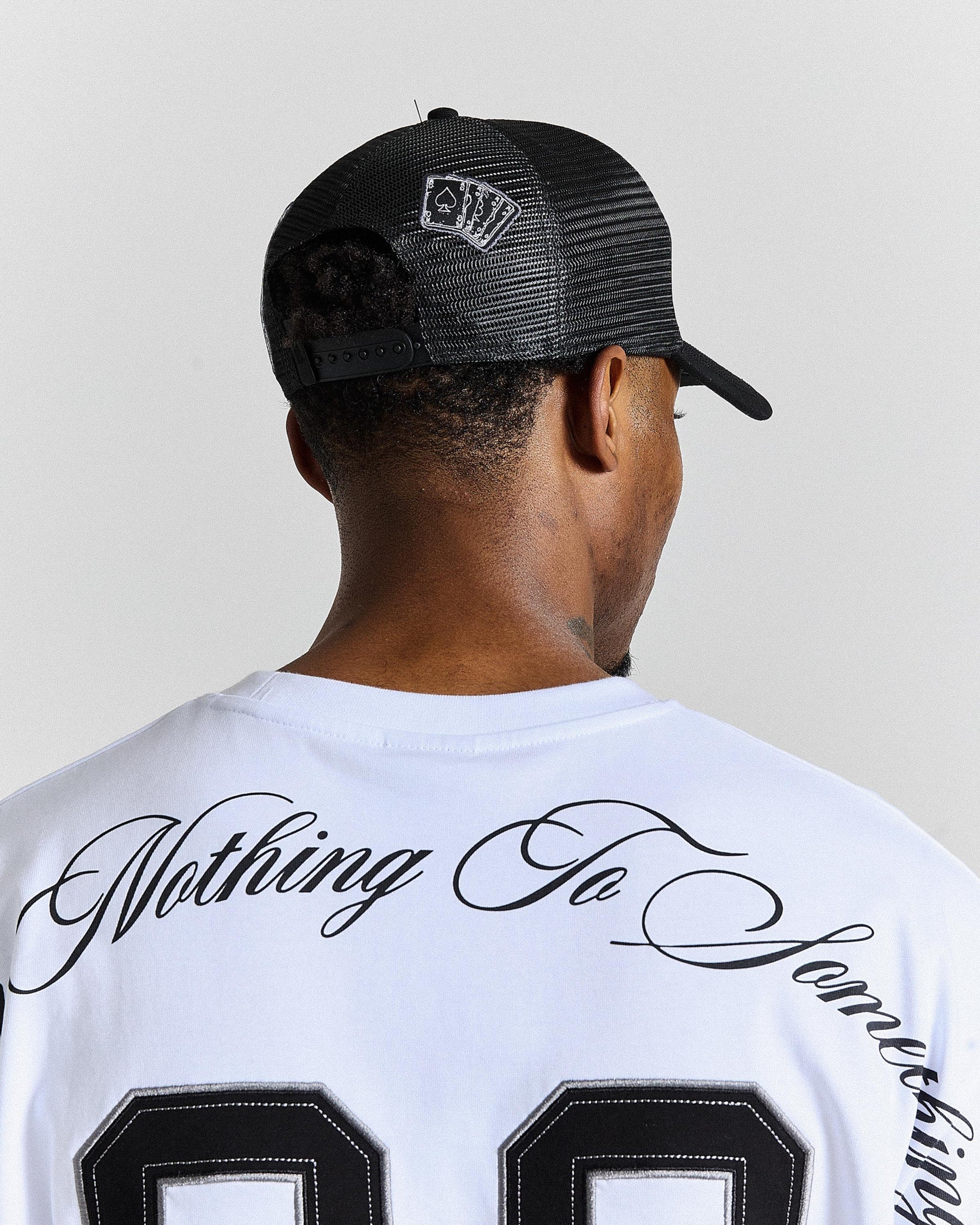 Person wearing a black cap and white t-shirt with text on a plain background