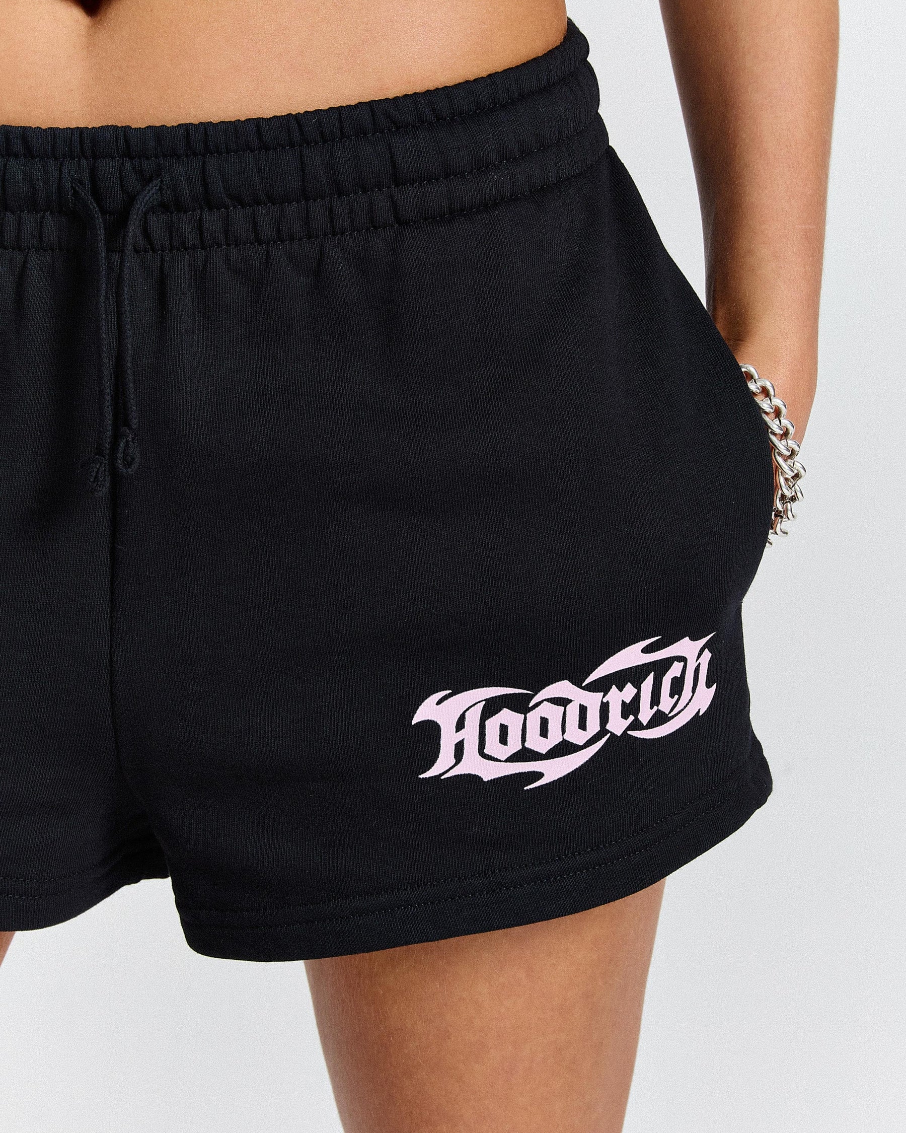 Black shorts with 'Hoodrich' logo worn by a person on a light gray background