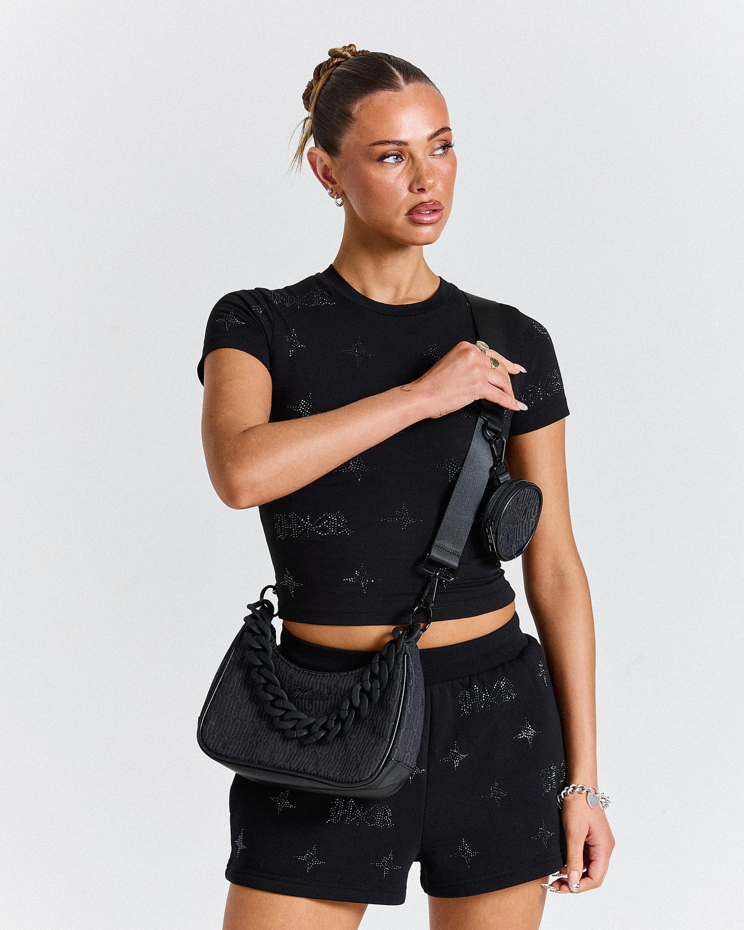 Woman wearing a black outfit with matching accessories on a plain background