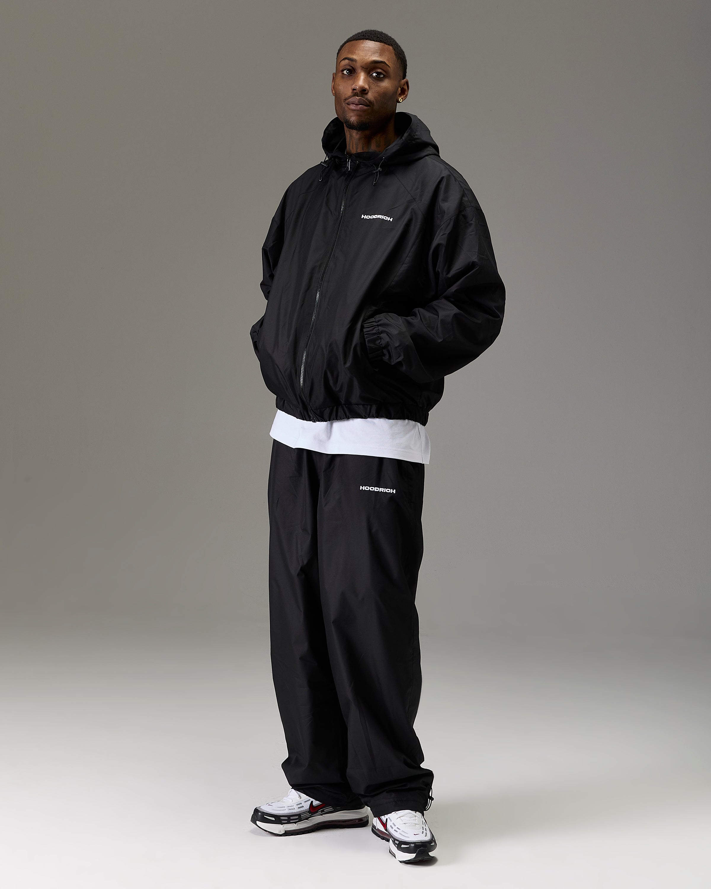 Displays a model wearing the Black 'Hoodrich' branded Men's The Winner's Circle Ripstop Woven Full Tracksuit