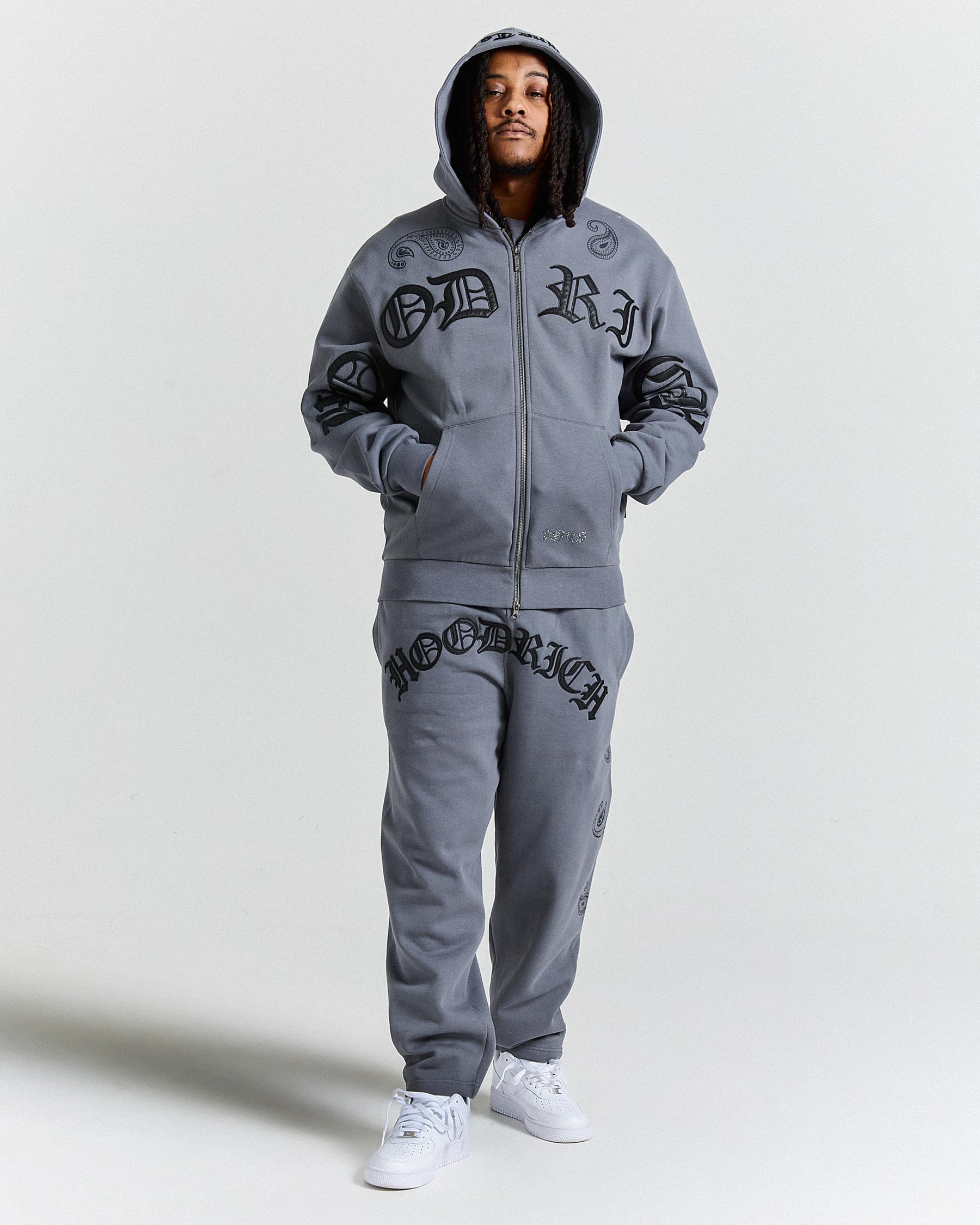 Person wearing a gray tracksuit with branding on a light gray background