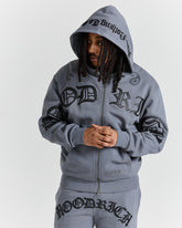 Person wearing a gray hoodie with branding on a white background