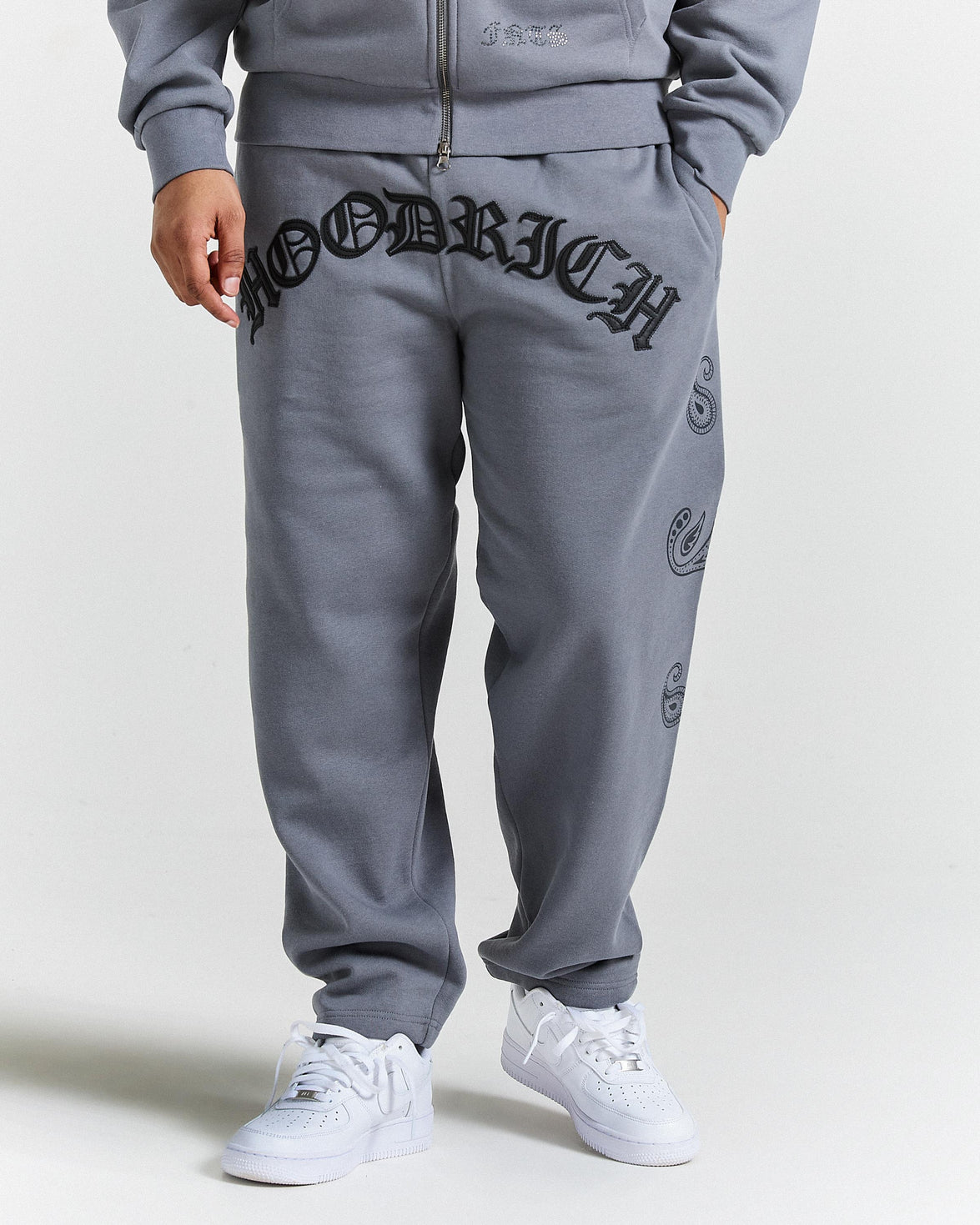 Person wearing gray sweatpants with branding on a white background
