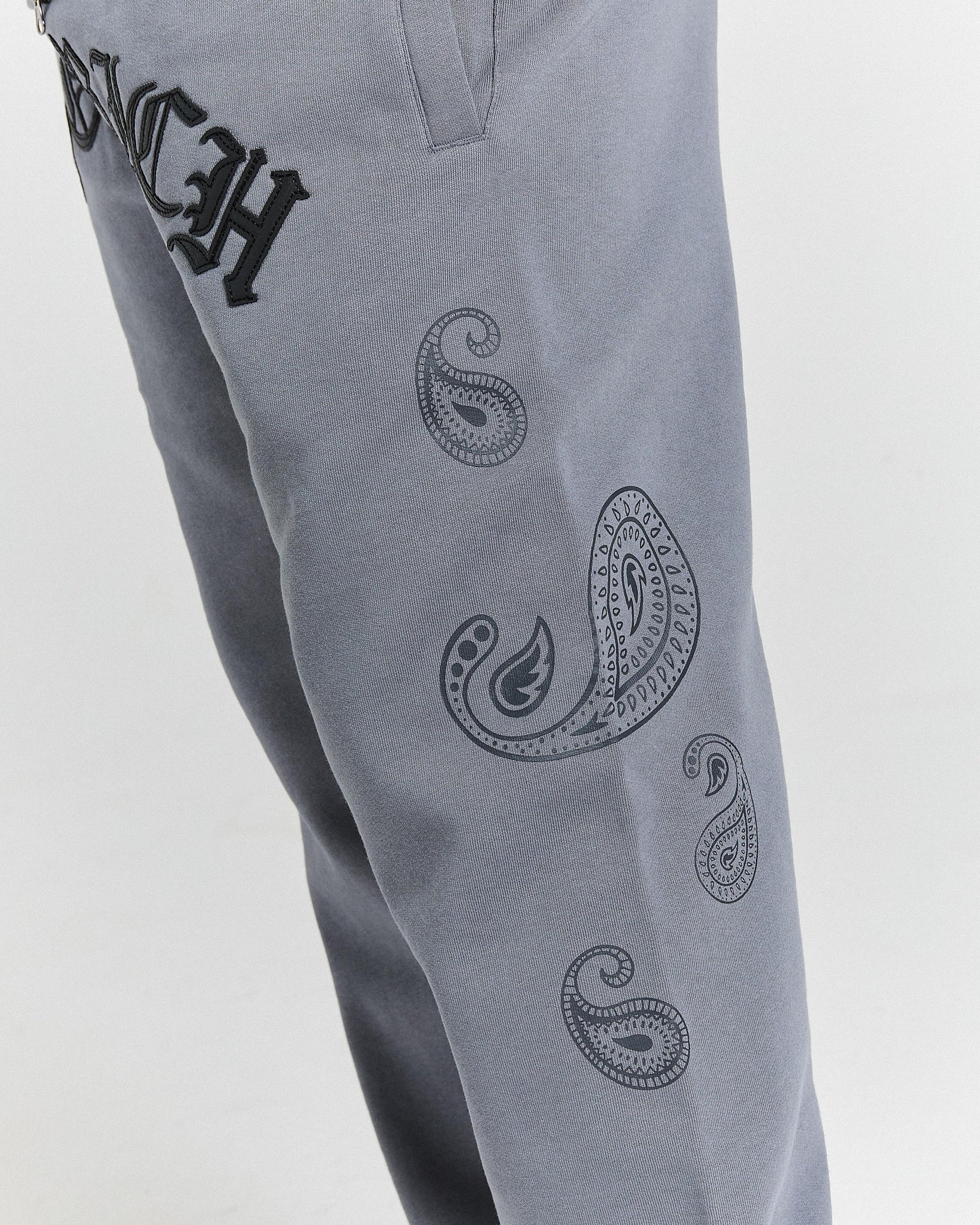 Gray pants with black paisley patterns and text on a light gray background