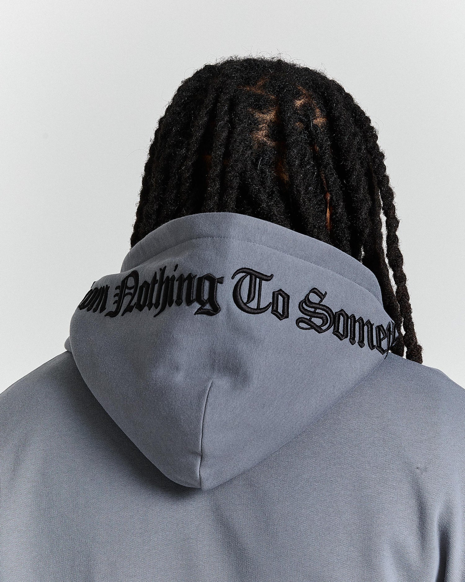 Person wearing a gray hoodie with text on the hood, facing away from the camera.