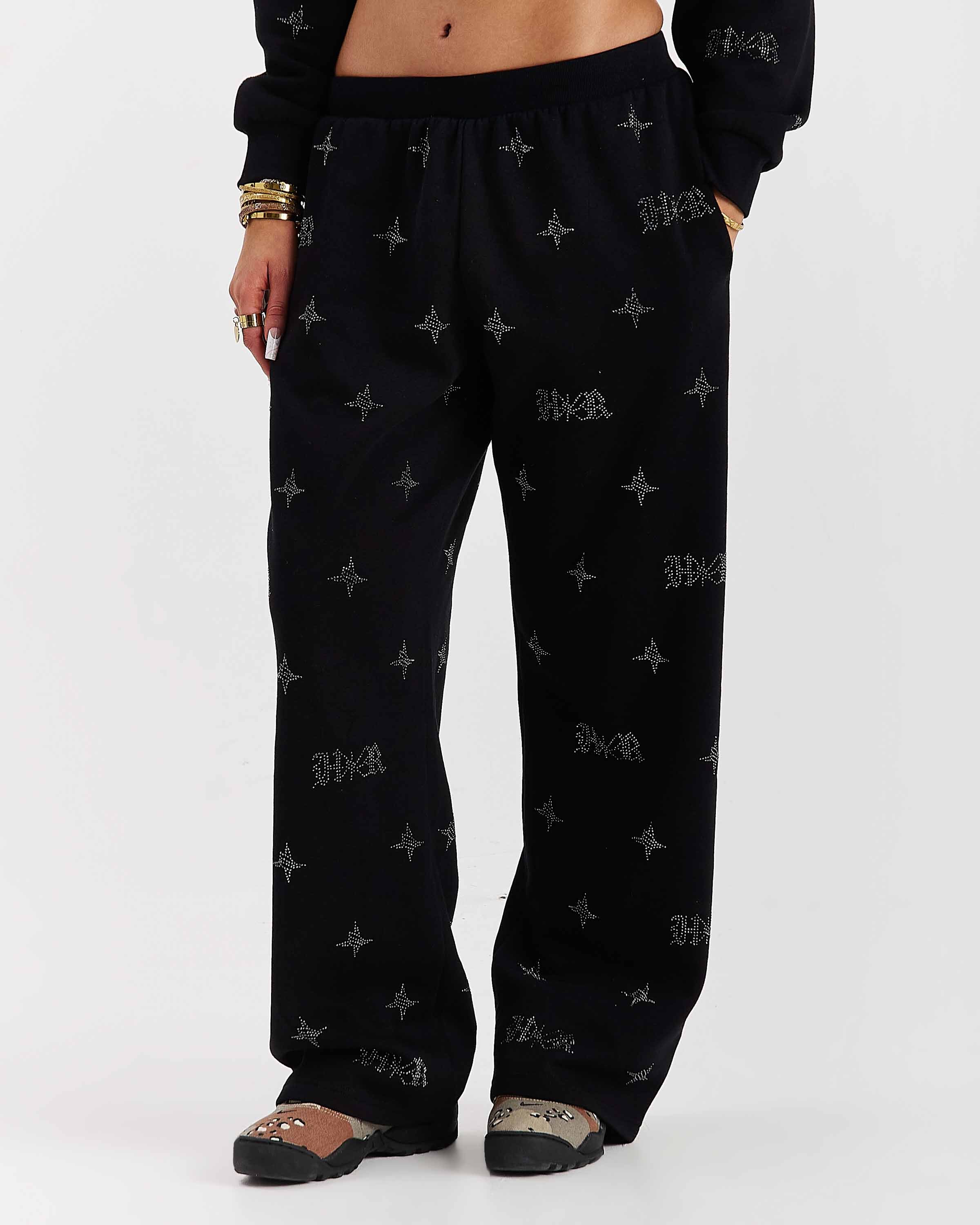 Person wearing black pants with patterns on a white background
