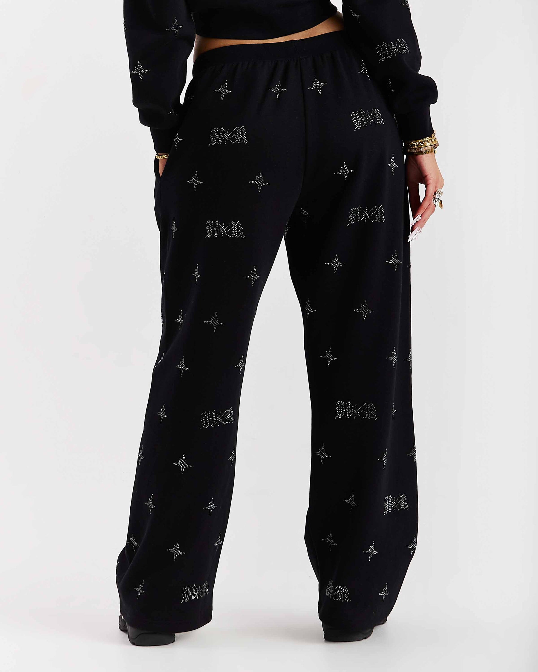 Black pants with a pattern worn by a person on a white background