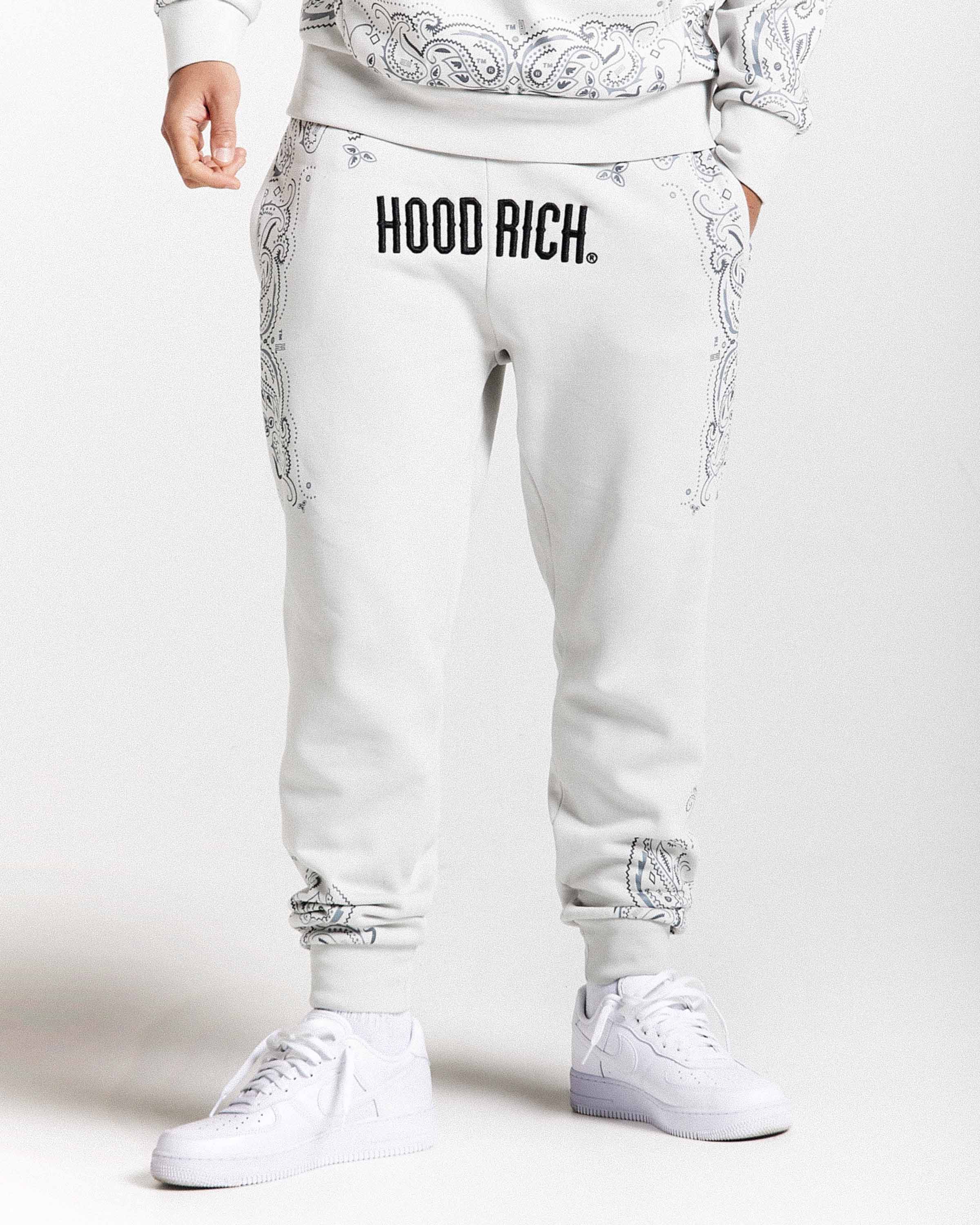 White jogger pants with 'HOOD RICH' text on a white background